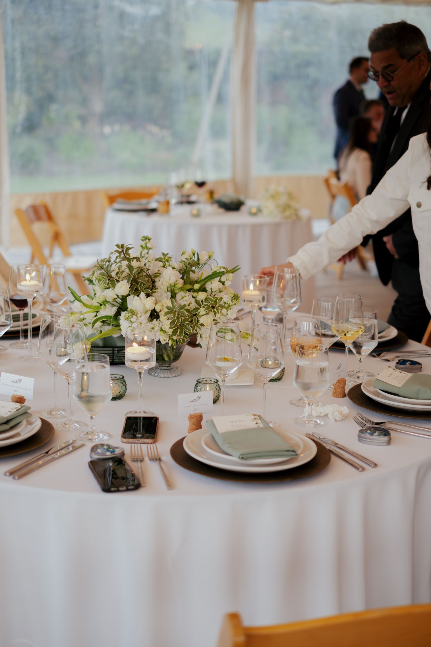 Elegant wedding reception table set with white linens, floral centerpiece, candles, and fine glassware.