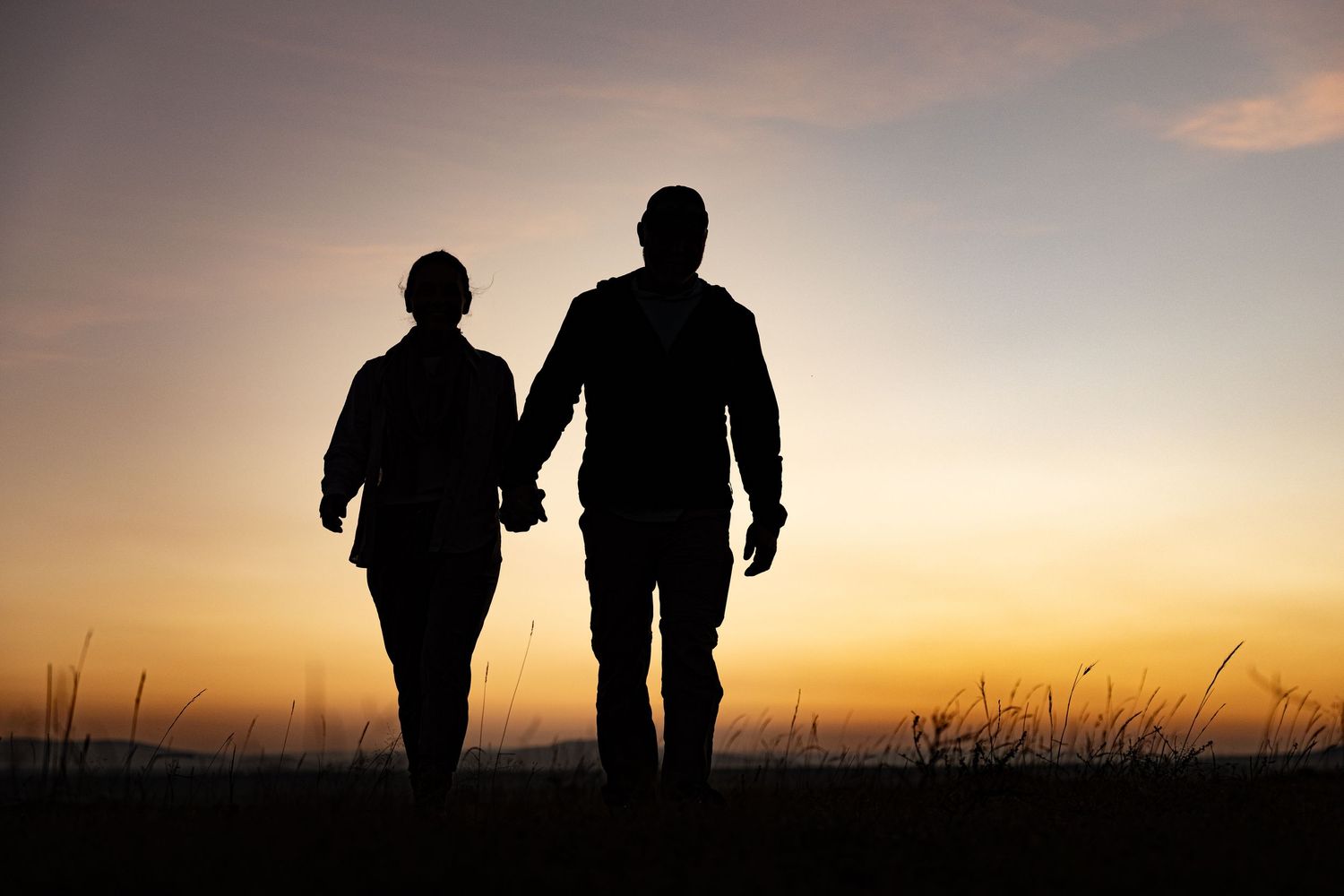 Silhouettes of people walking along a ridge during golden hour in Africa.