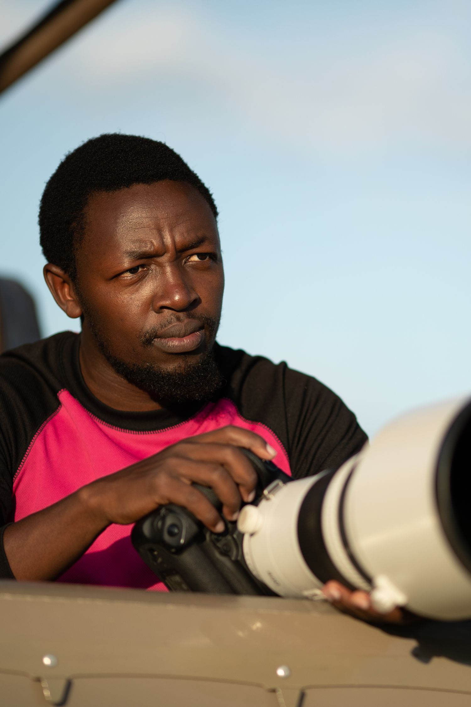 Wildlife photographer using professional telephoto lens equipment during safari.