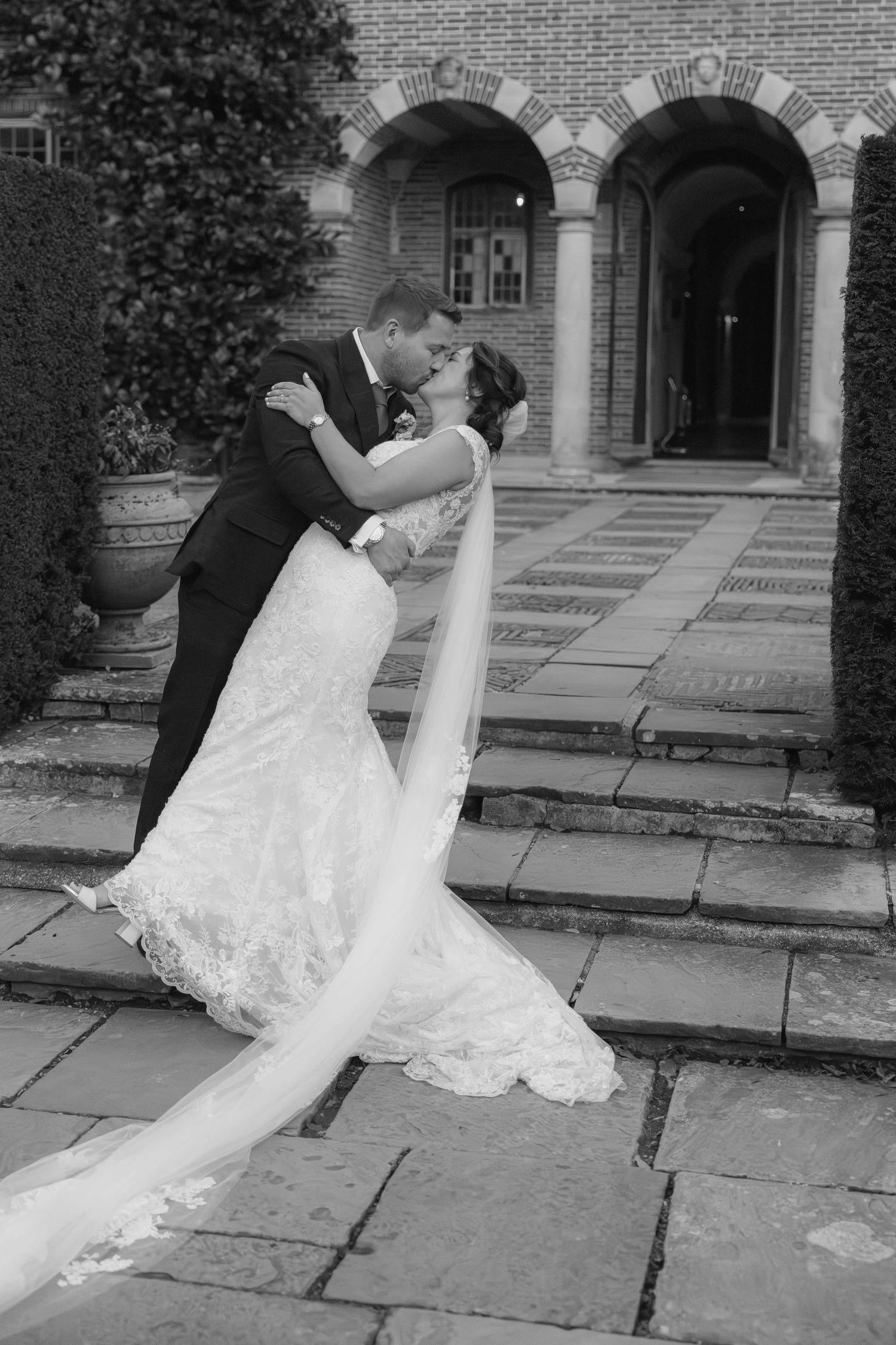 Black and white wedding photo sequence showing a romantic dip pose on stone pavement.
