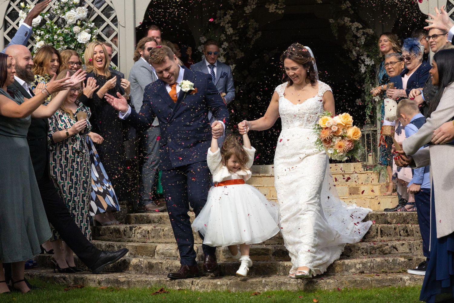Wedding party celebrates on outdoor stone steps surrounded by guests.