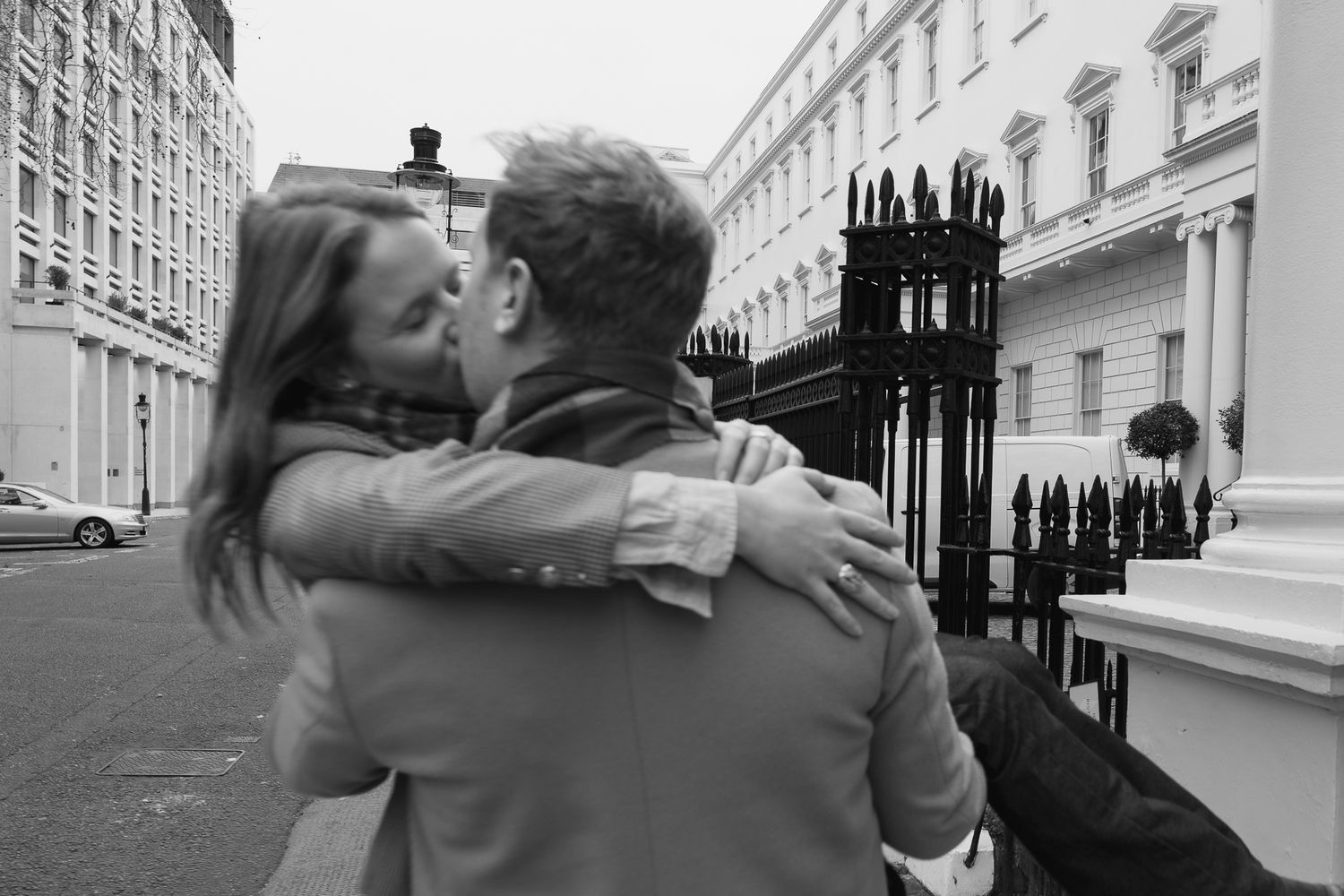 Black and white photo of a couple sharing an intimate moment on a city street.