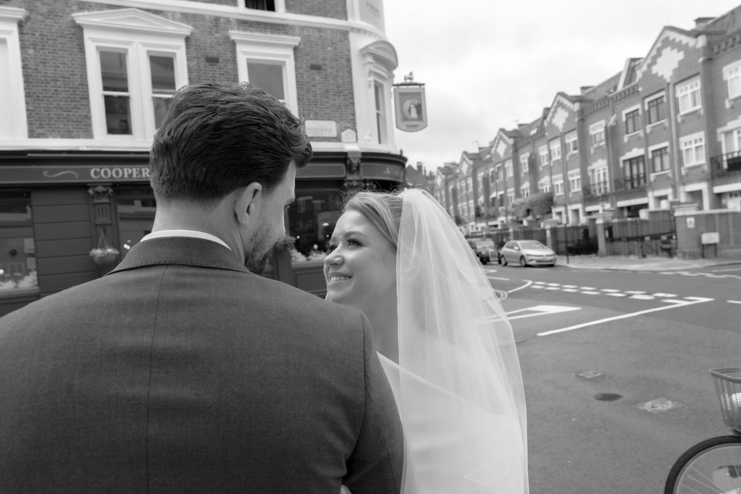 Black and white photo of a bride and groom sharing a moment on a city street on their wedding day.