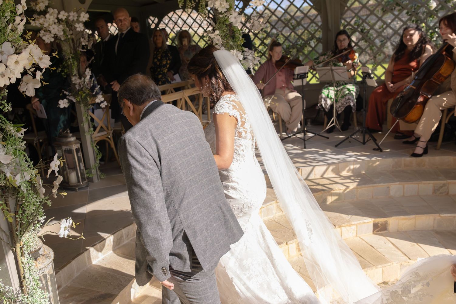 A wedding reception venue decorated with greenery and floral arrangements as guests mingle and celebrate.