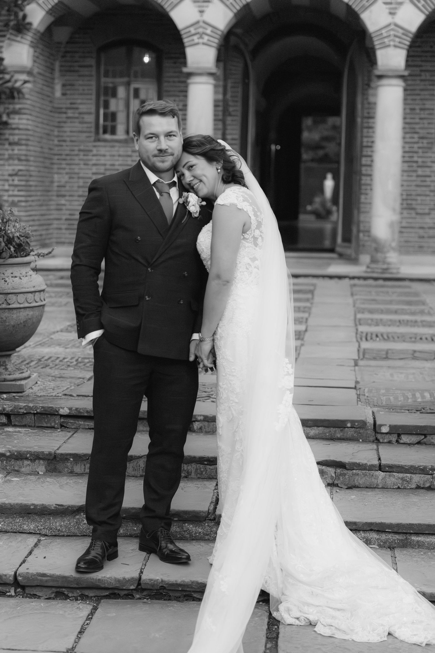 Romantic black and white wedding portraits on brick steps showing tender moments between newlyweds.