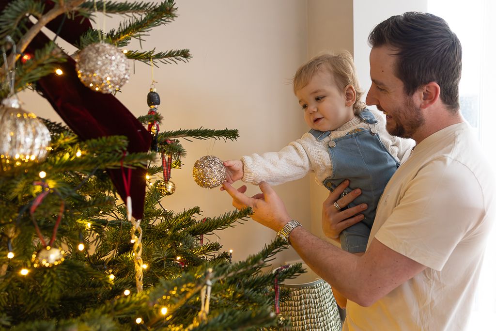 Family decorating Christmas tree together with warm glowing lights.