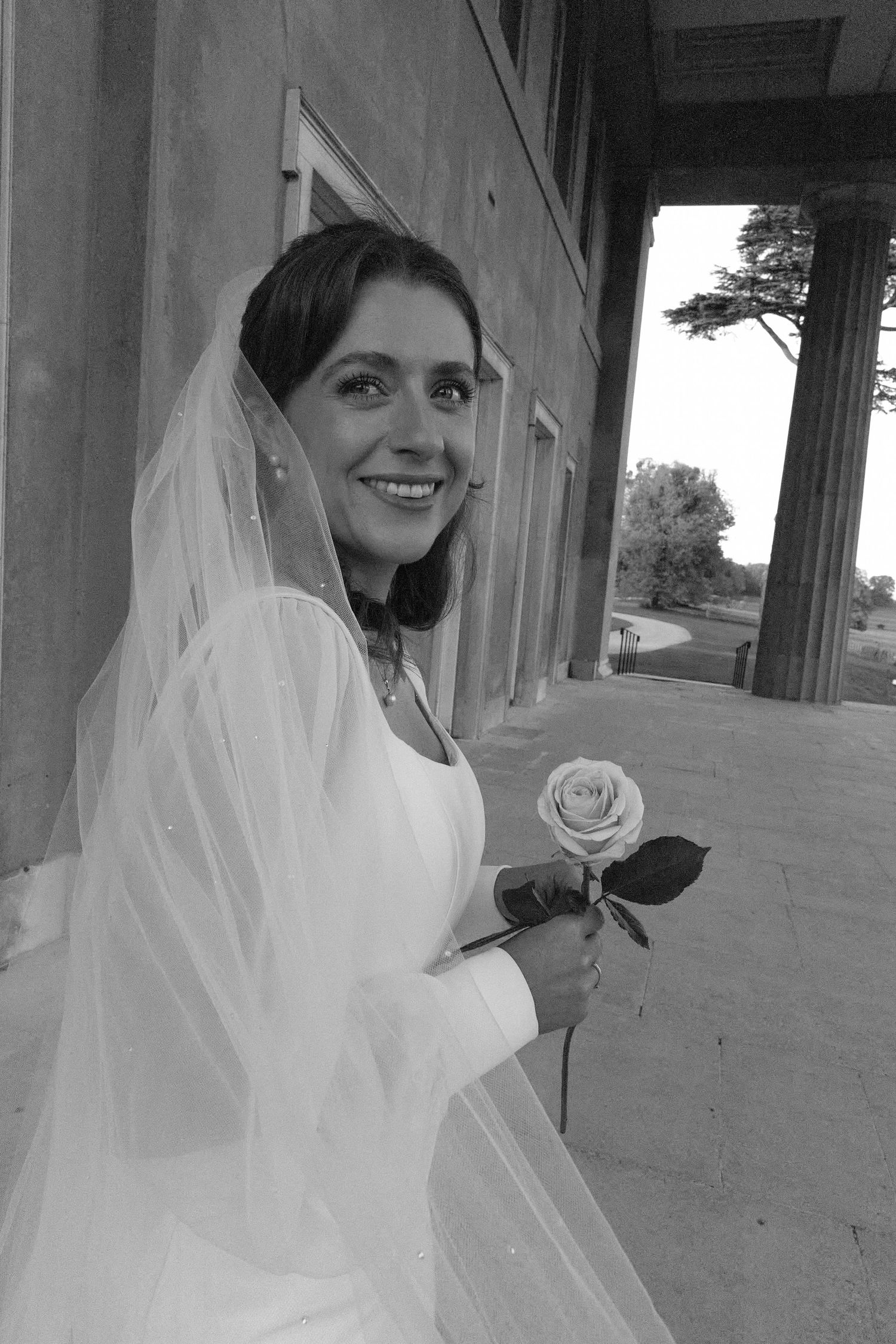 An artistic black and white wedding photo featuring a person with a flowing veil.