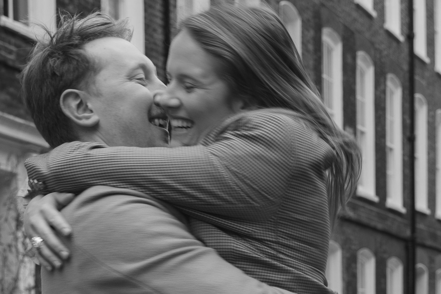 A romantic black and white photo of a couple embracing outdoors.