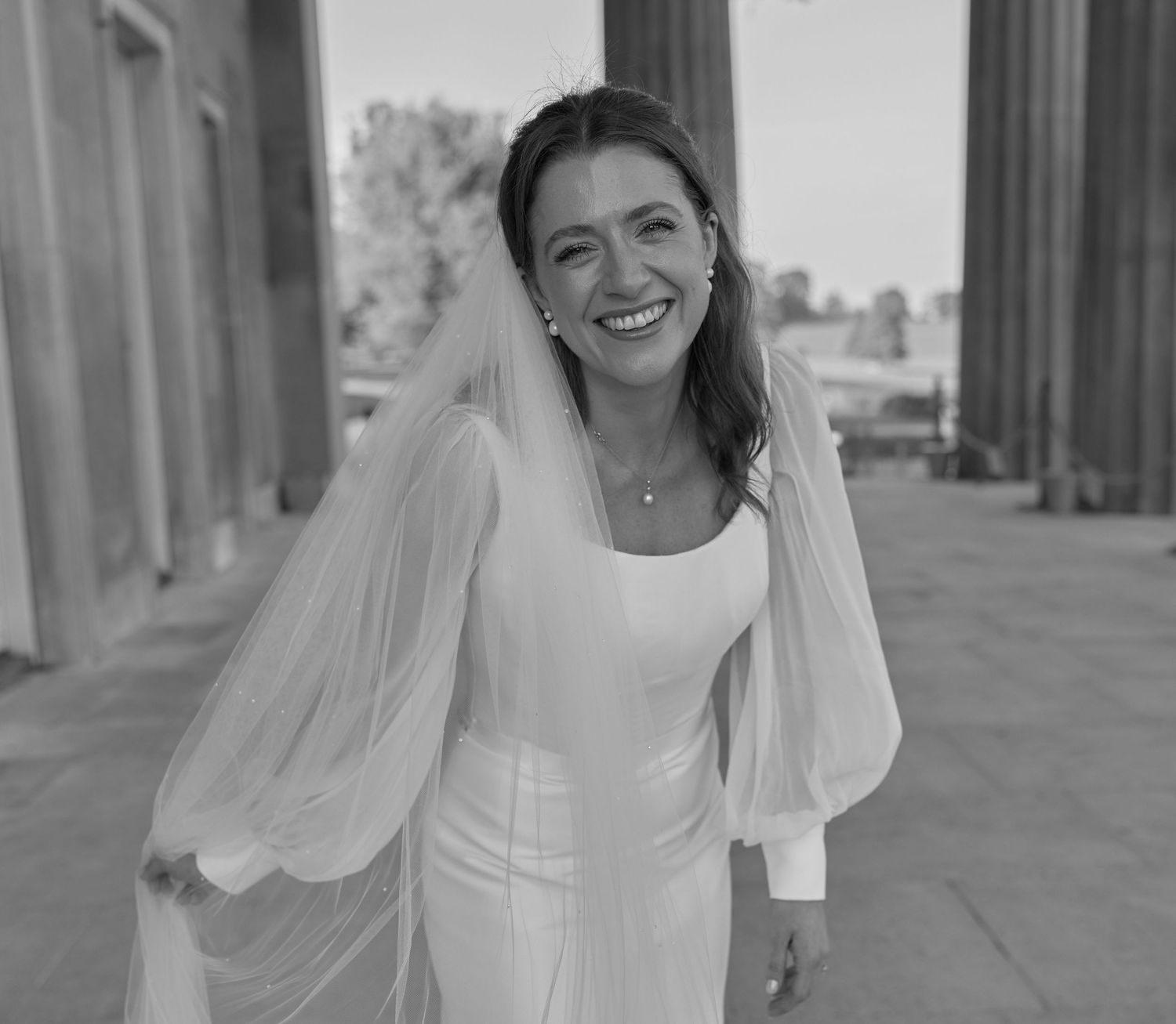 A black and white portrait of a bride in a classic white wedding dress with puff sleeves.