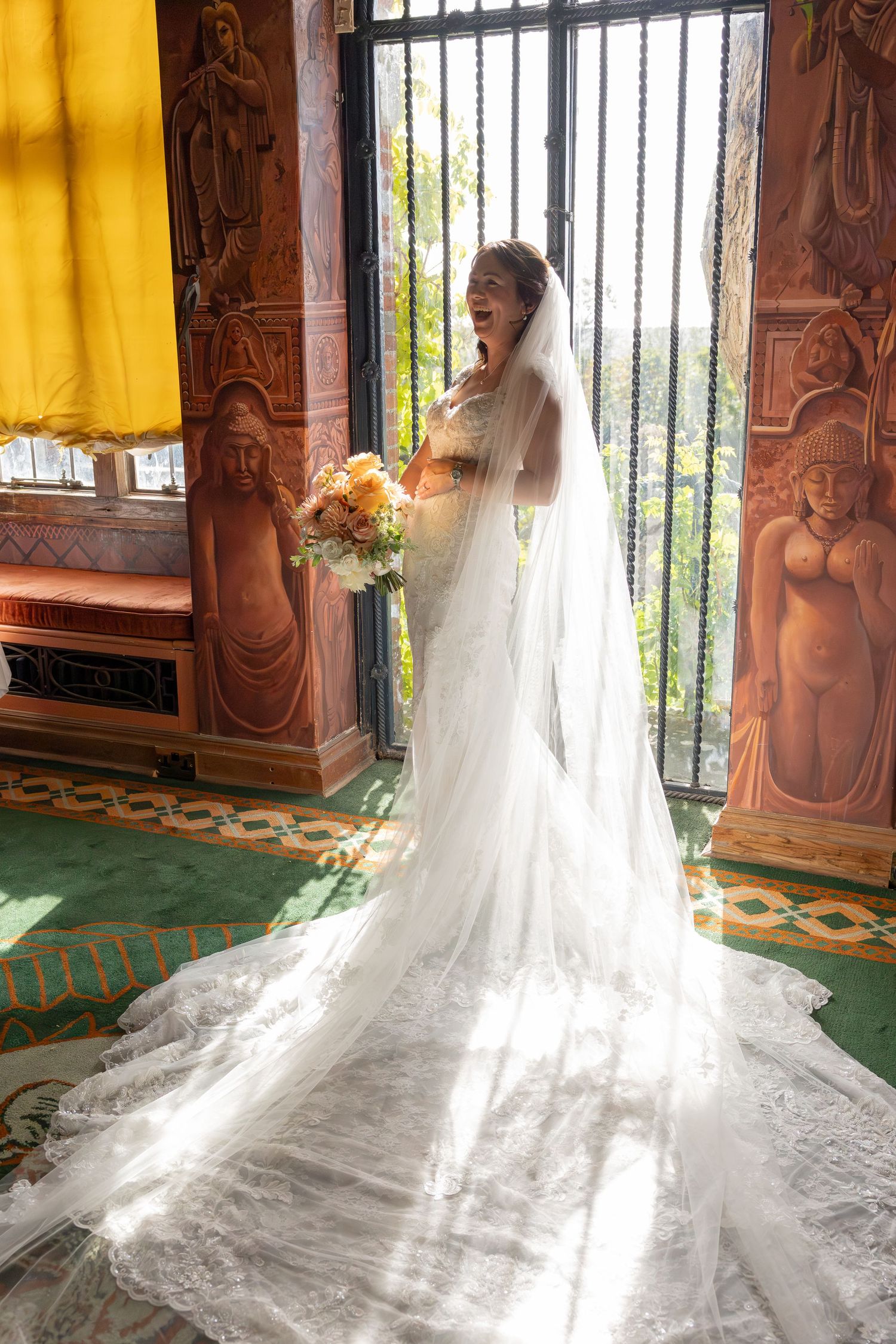 Stunning white wedding dress with long lace train displayed in elegant room with ornate decor.