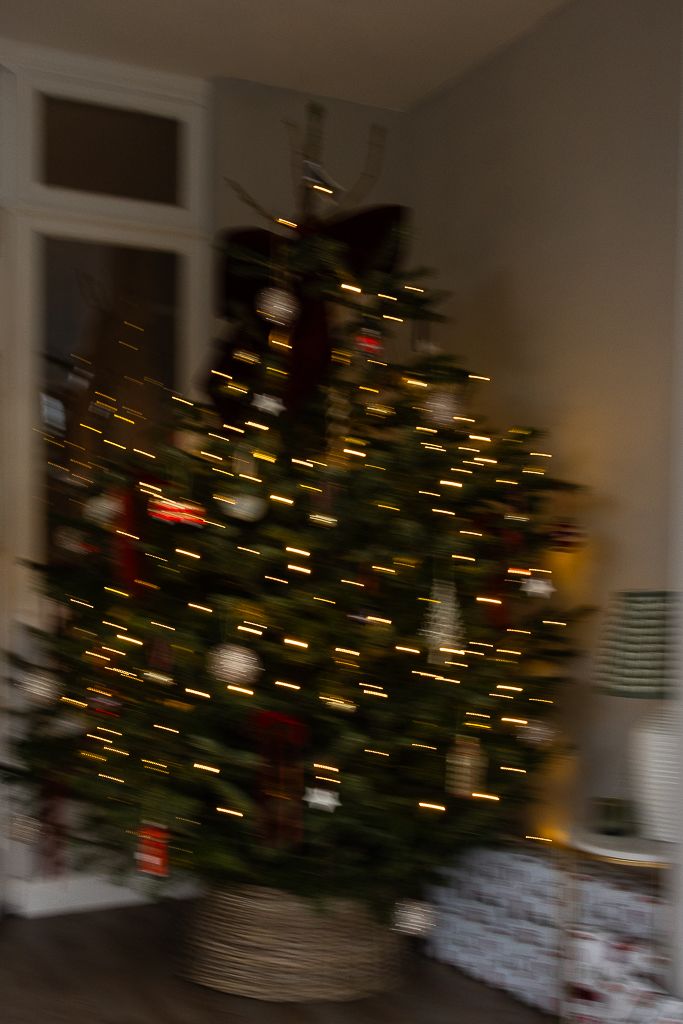 Abstract motion blur of Christmas tree lights creating bokeh effect in dark room.