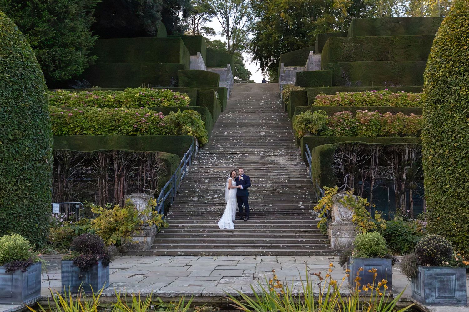 Garden wedding venue with manicured hedges and stone steps leading up a terraced hillside.