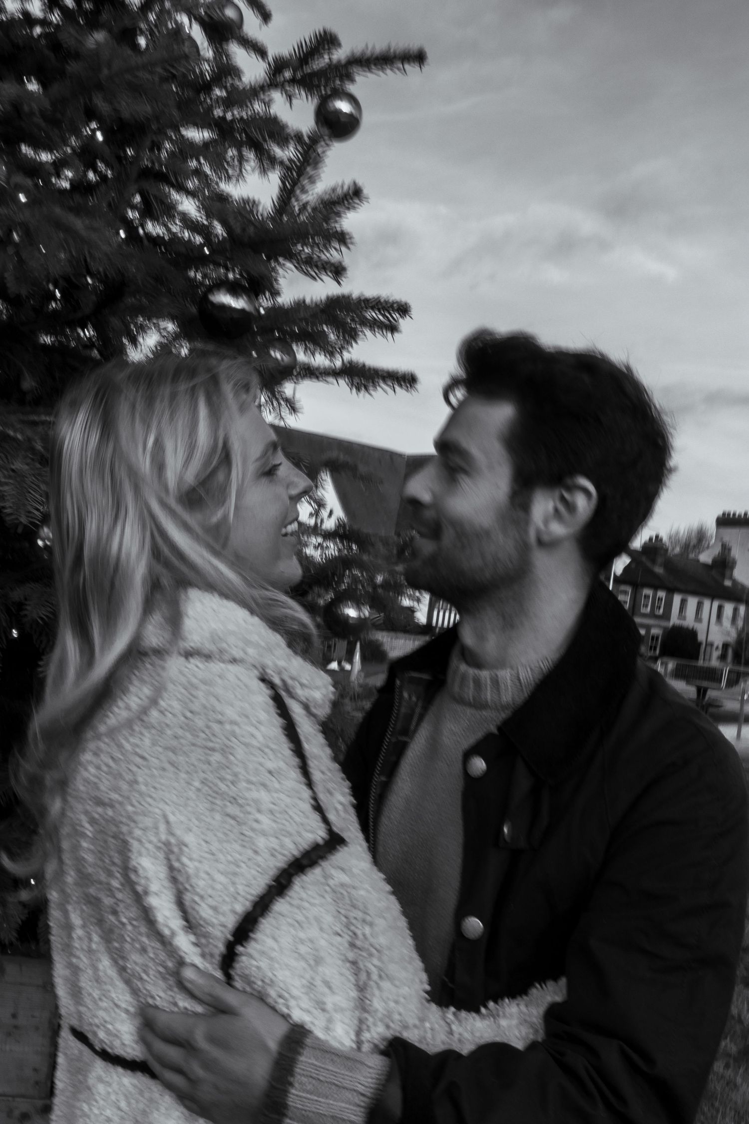 A couple in contrasting black and white outerwear share a romantic moment outdoors.