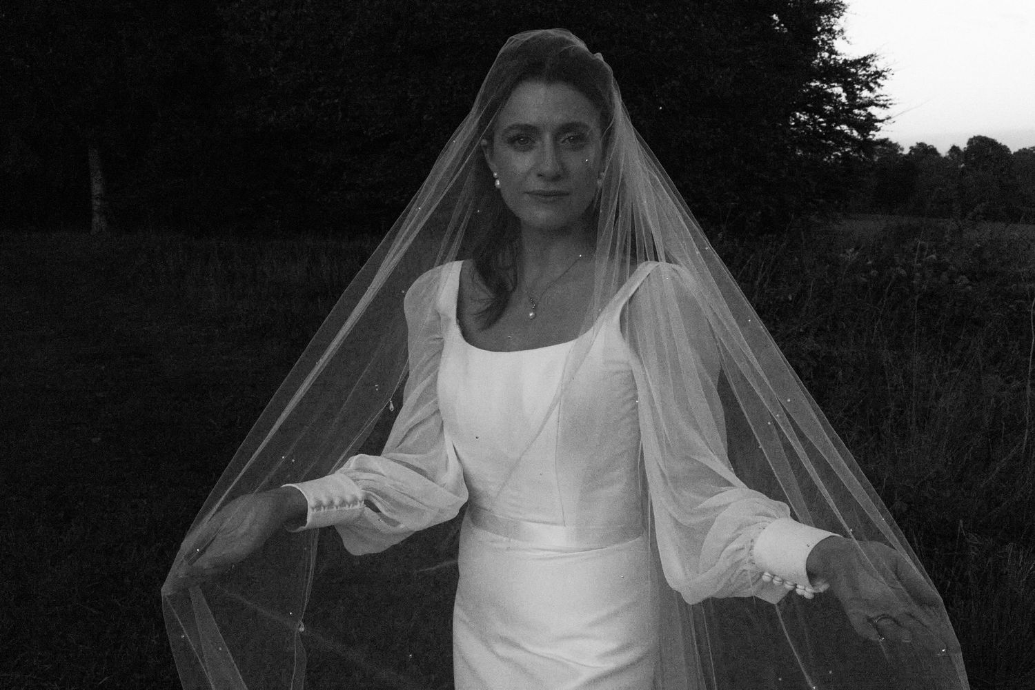 Black and white bridal portrait showing flowing veil movement in an outdoor setting.