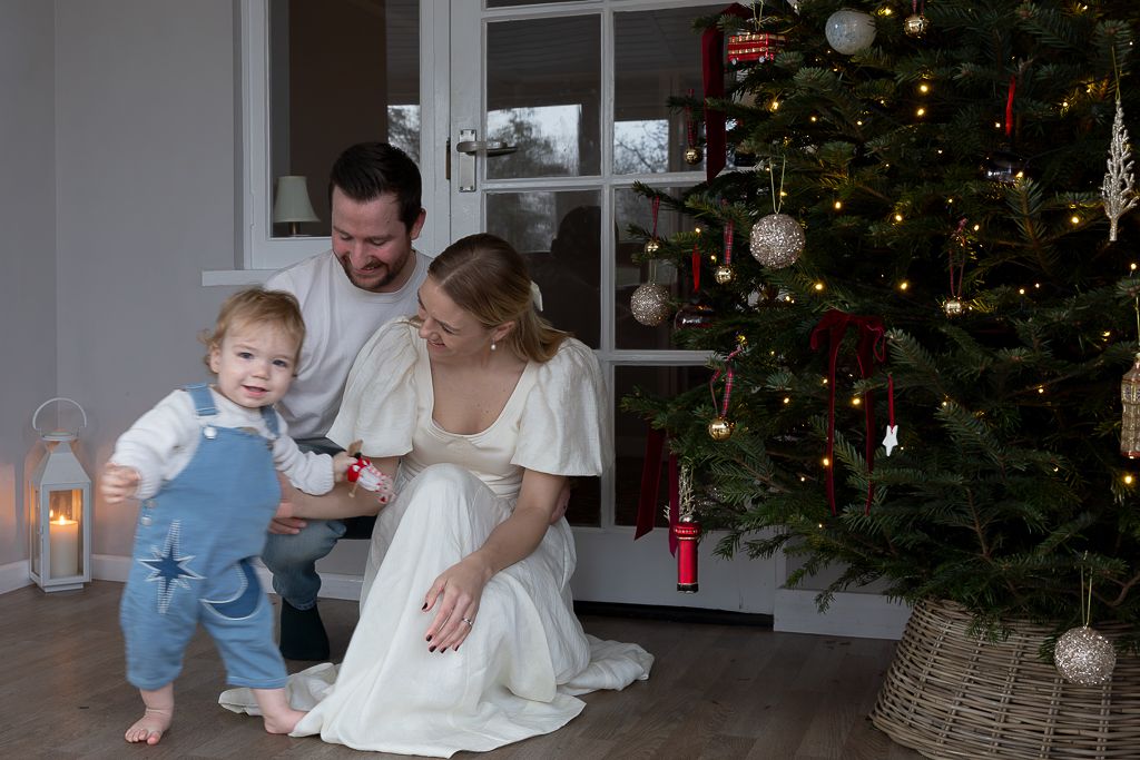 A family gathers around a decorated Christmas tree in their home, sharing a tender moment together.