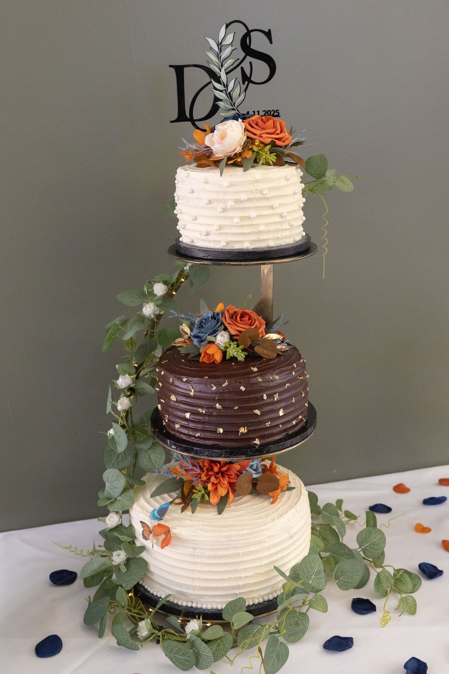 Two-tiered wedding cake decorated with chocolate ganache, white frosting, orange flowers and eucalyptus.