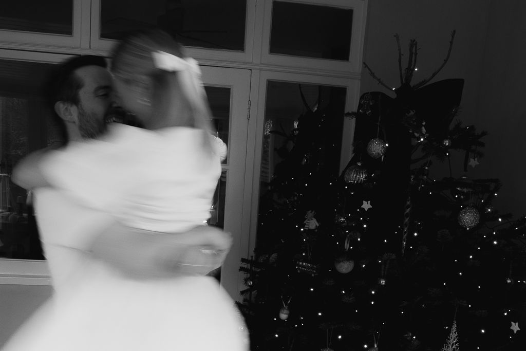 A blurred motion shot of two people dancing near a decorated Christmas tree.