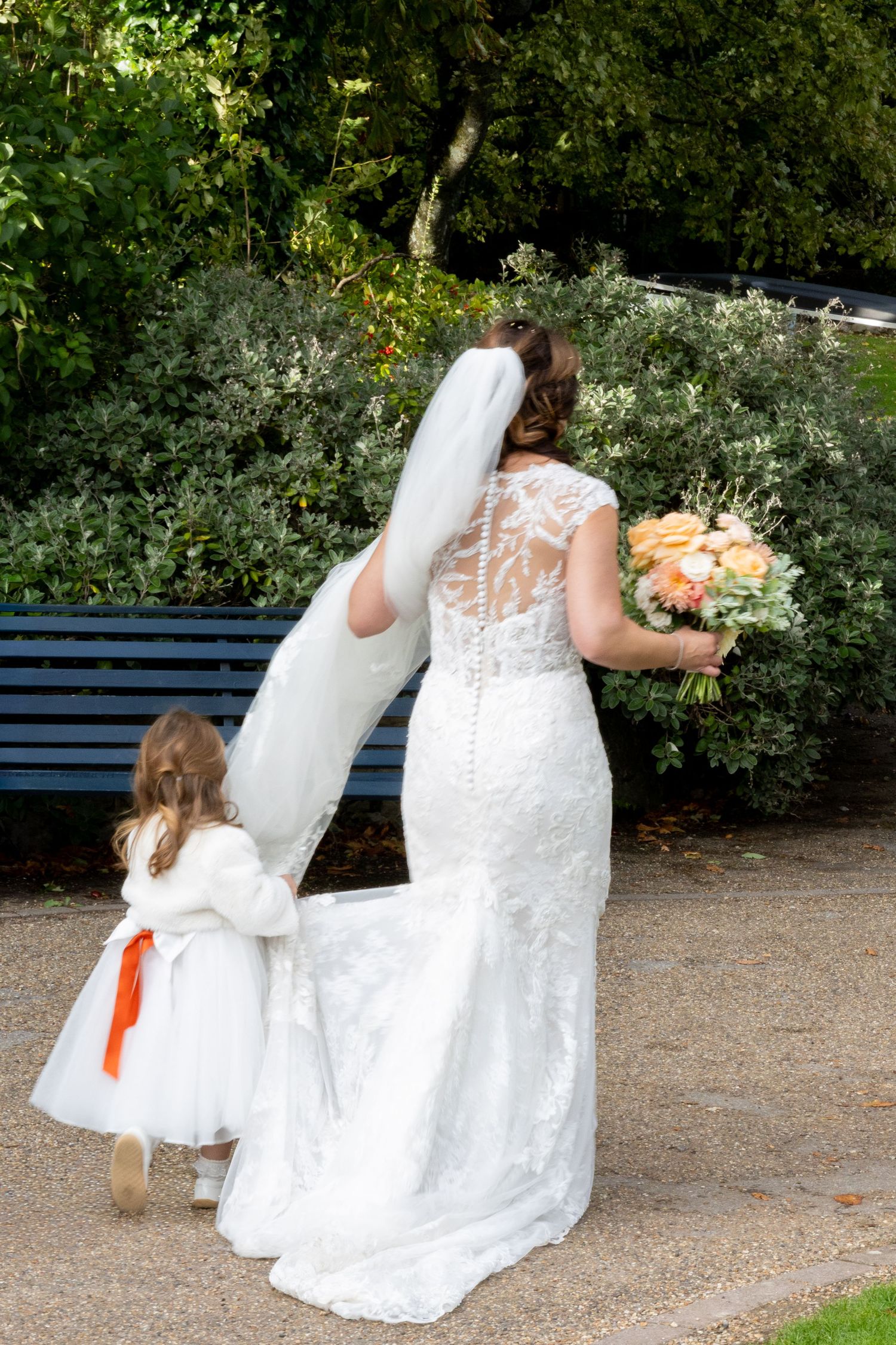A sequence of wedding photos showing a bride and flower girl sitting together on a park bench.