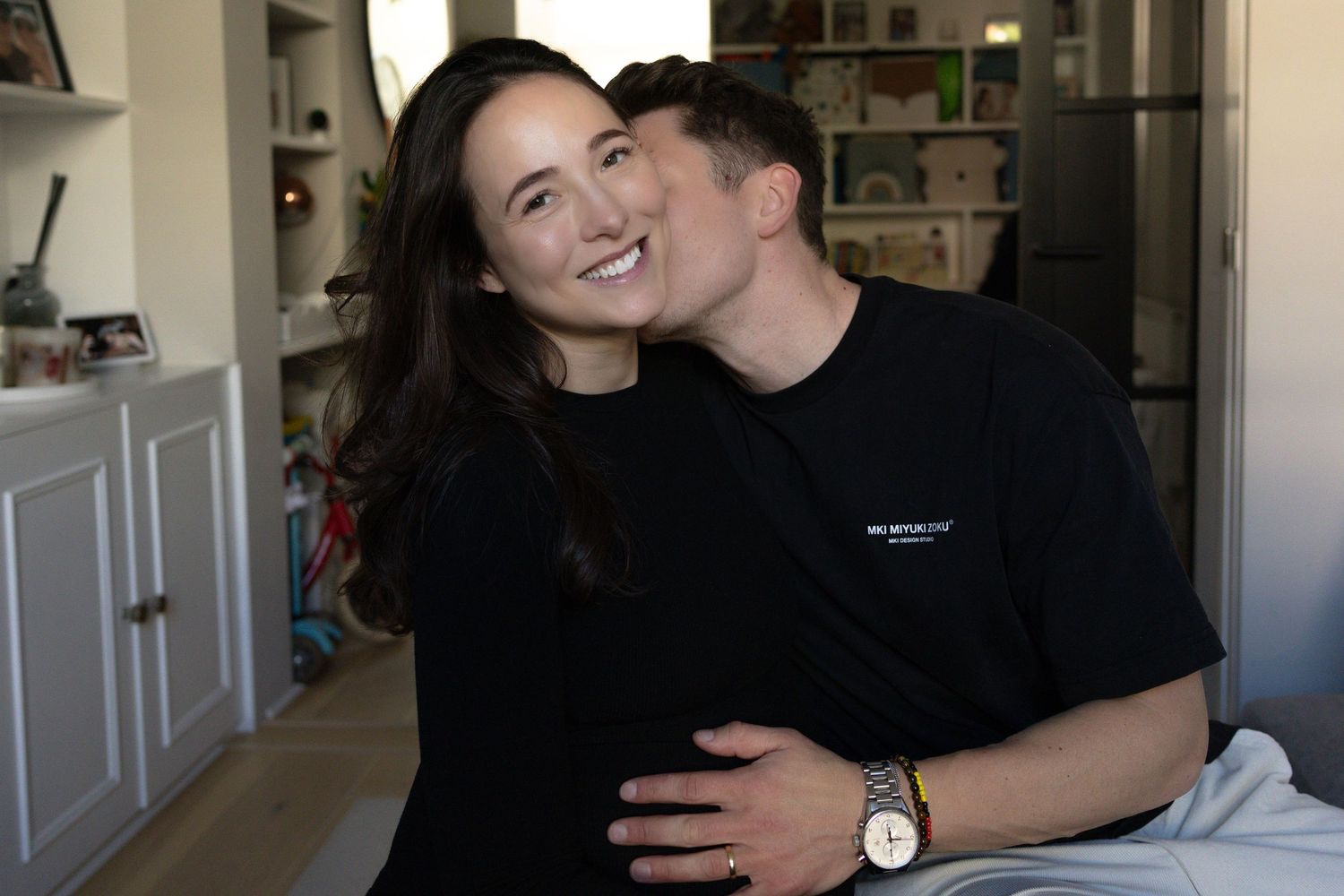 Happy couple sharing tender moment at home, man kissing womans cheek affectionately.