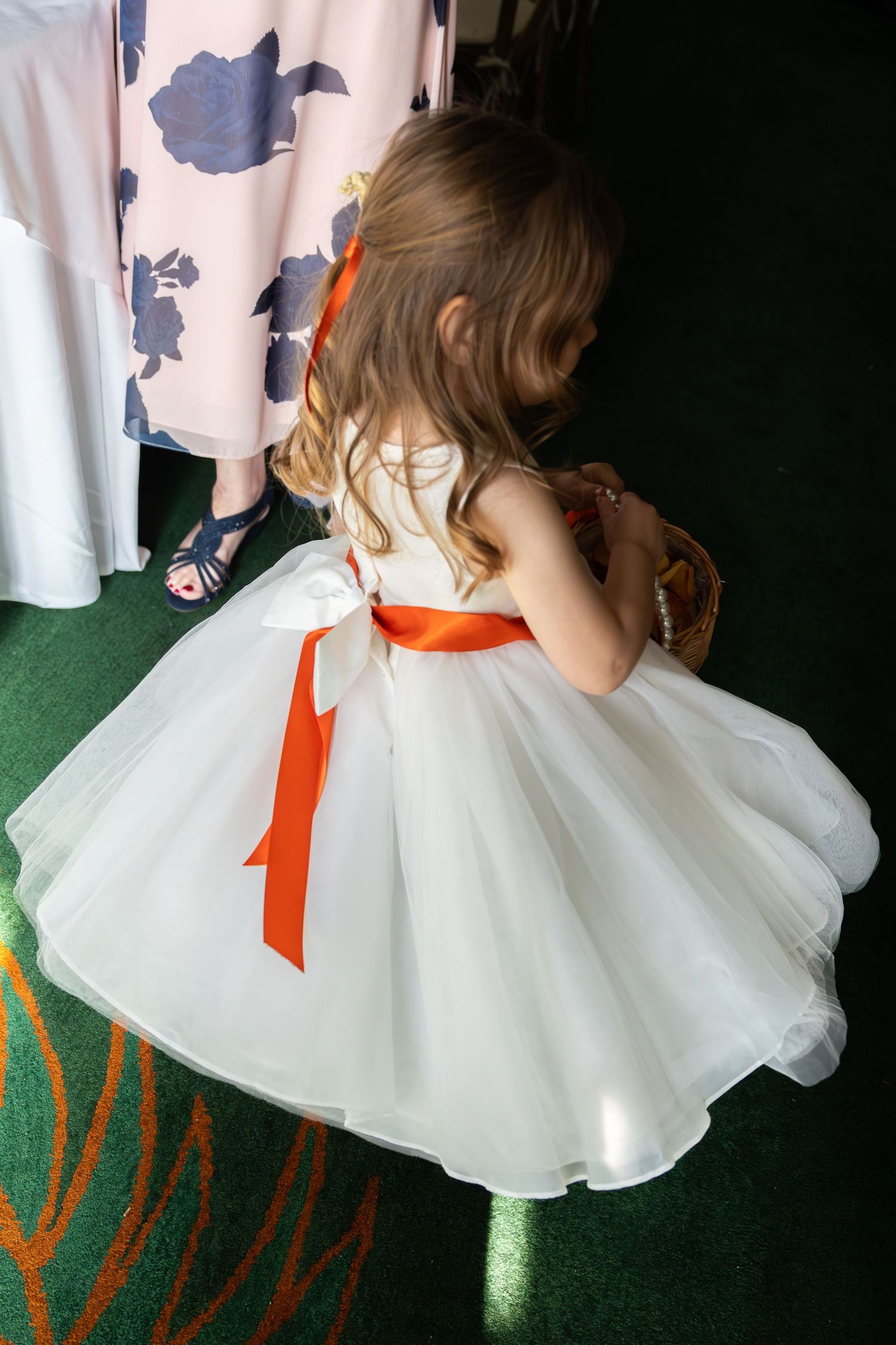 White tulle dress with orange ribbon accent shown from different angles on display.