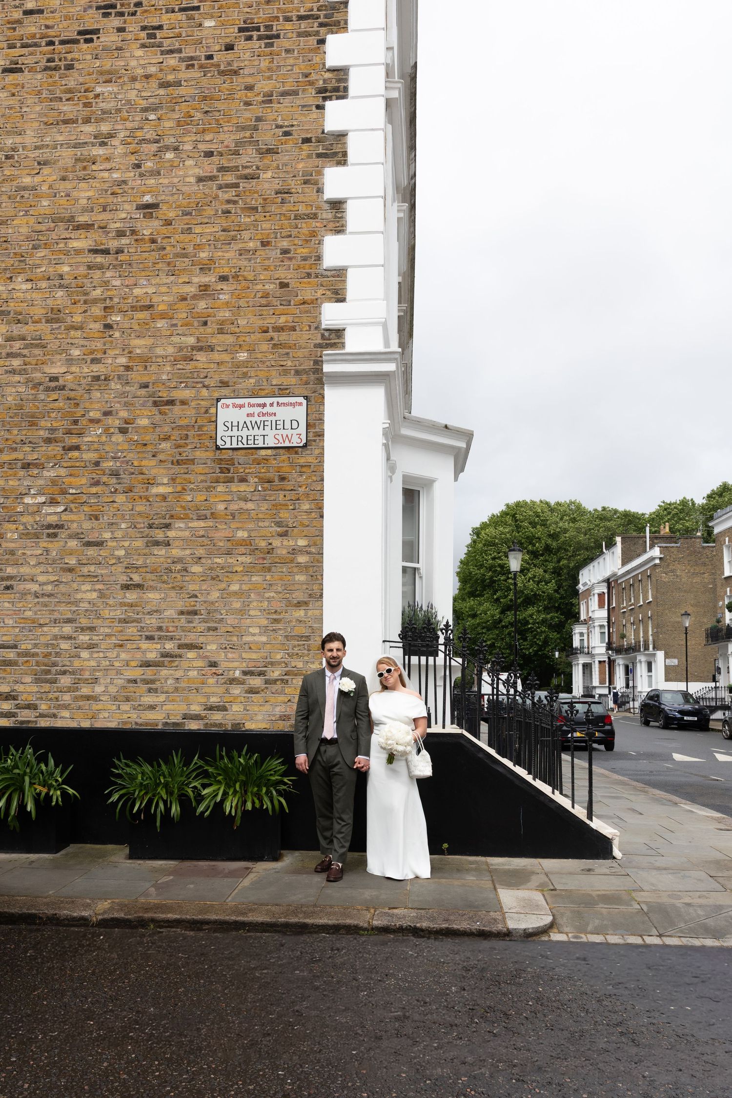 Bride and groom pose together on Shawfield Street corner in London on their wedding day.