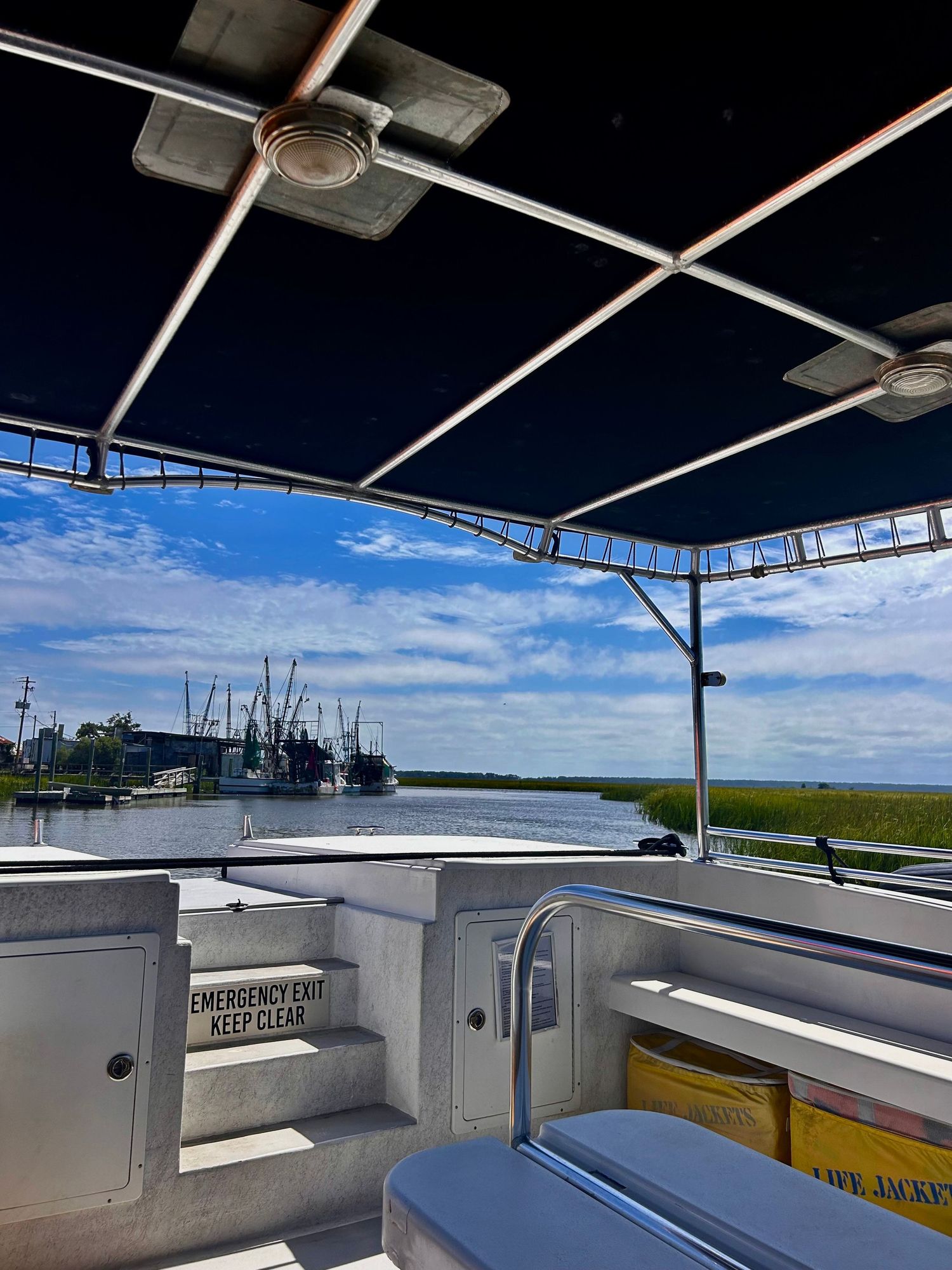 Interior view of a boat's helm station showing white panels and controls under a covered console with blue sky visible.