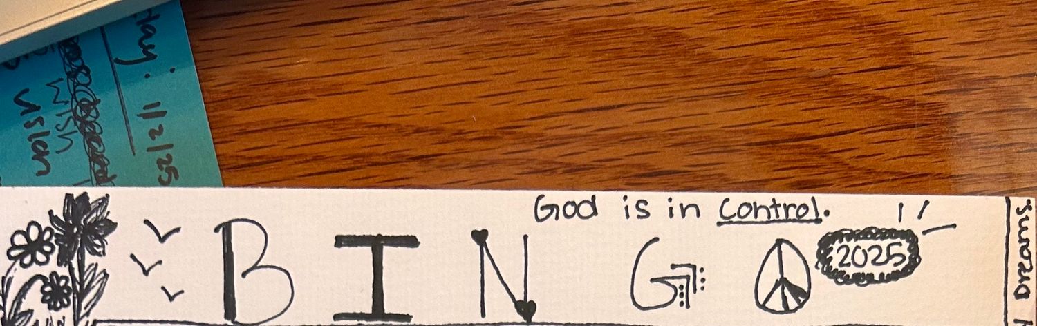 A wooden table with the word 'BINGO' written at the top and a peace symbol sketched on brown paper or cardboard.