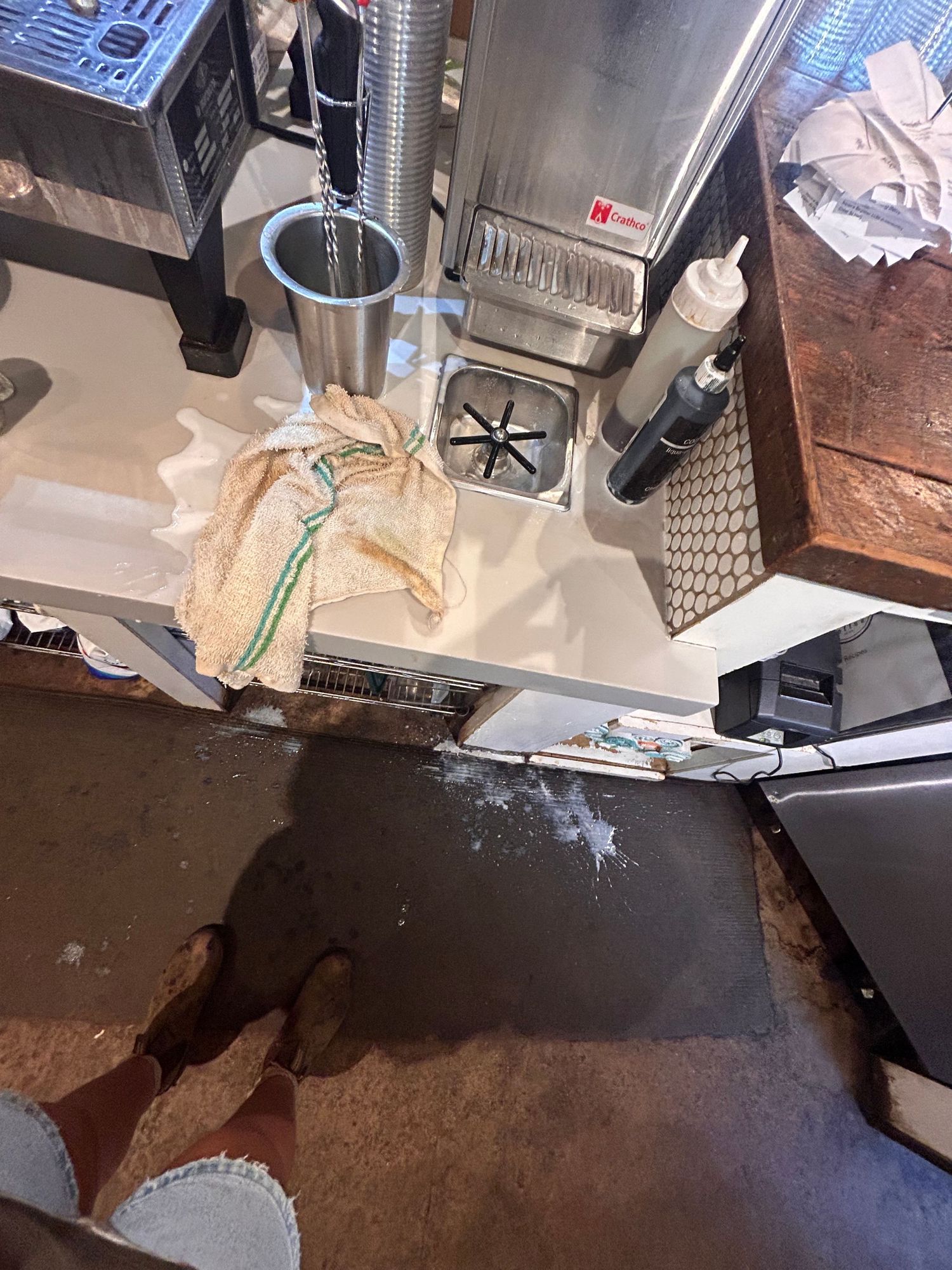 Equipment and supplies scattered on a stainless steel restaurant kitchen counter with food service items visible.
