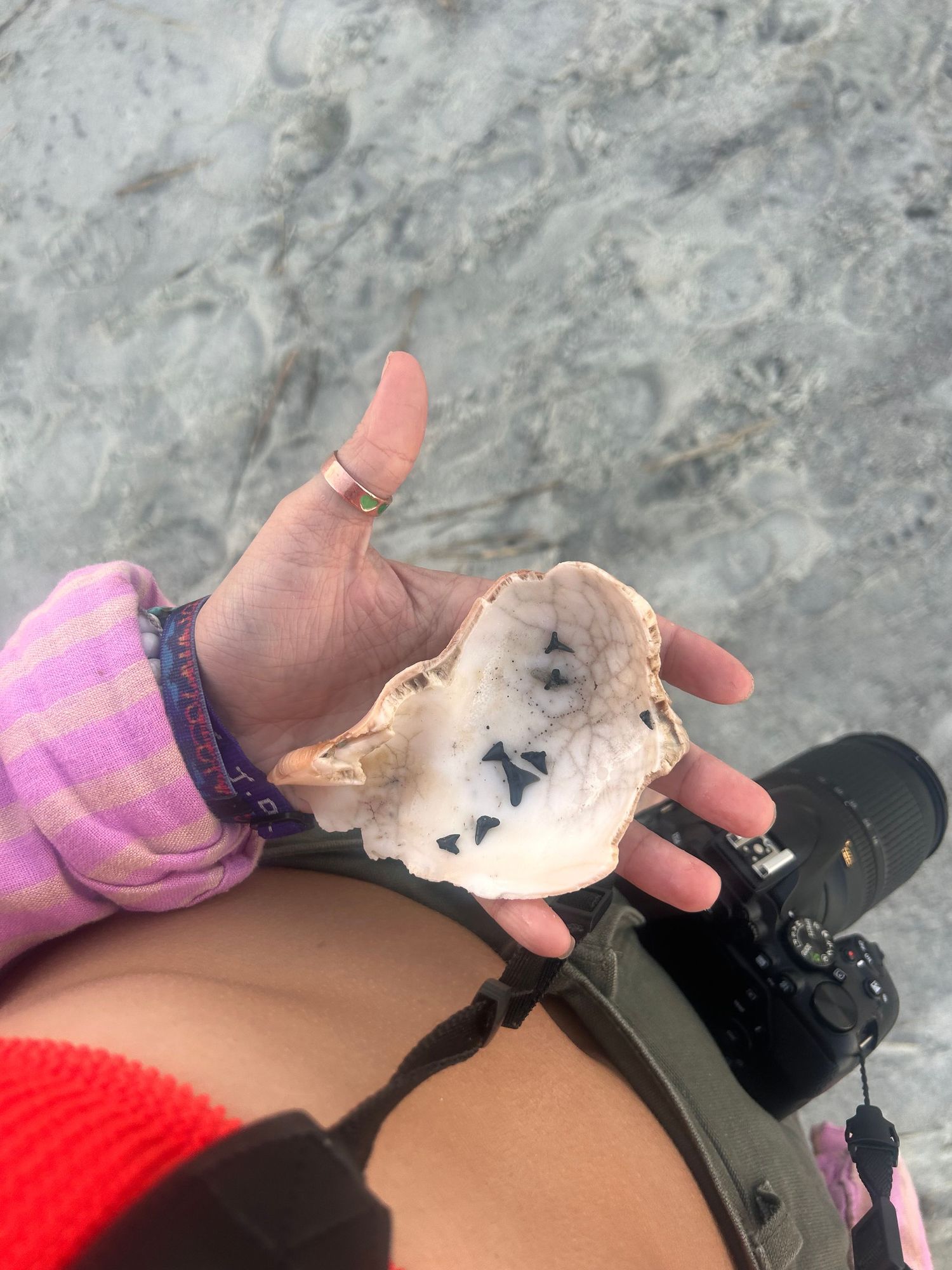 A hand wearing a purple bracelet holds up a broken geode crystal revealing sparkly mineral formations inside.