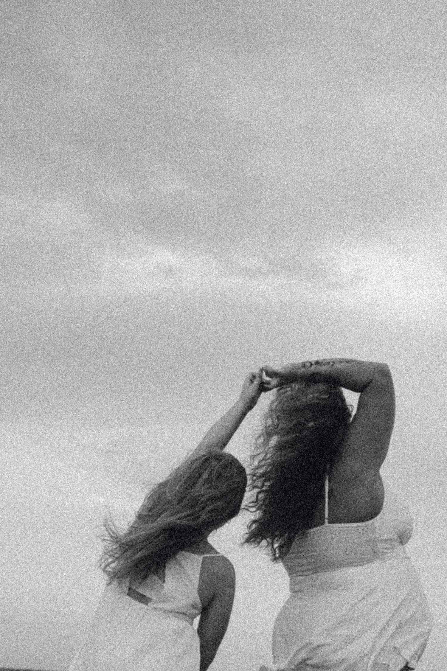 Black and white artistic sequence showing figures with hair flowing in the wind creating dynamic motion against sky.