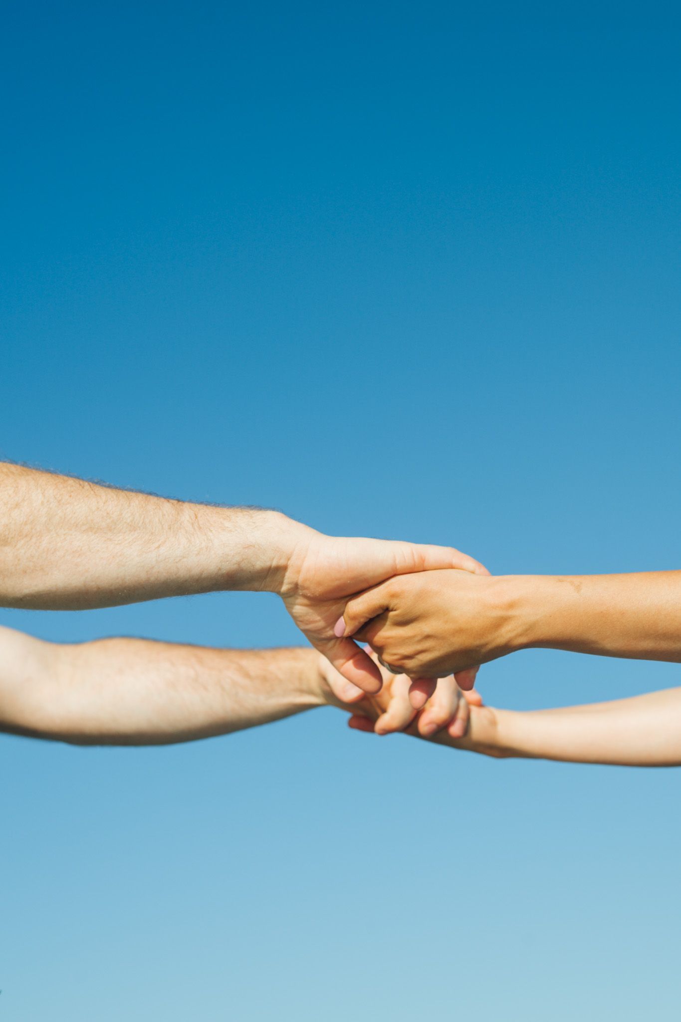 Two hands reaching towards each other against a bright blue sky background in a series of connected images.