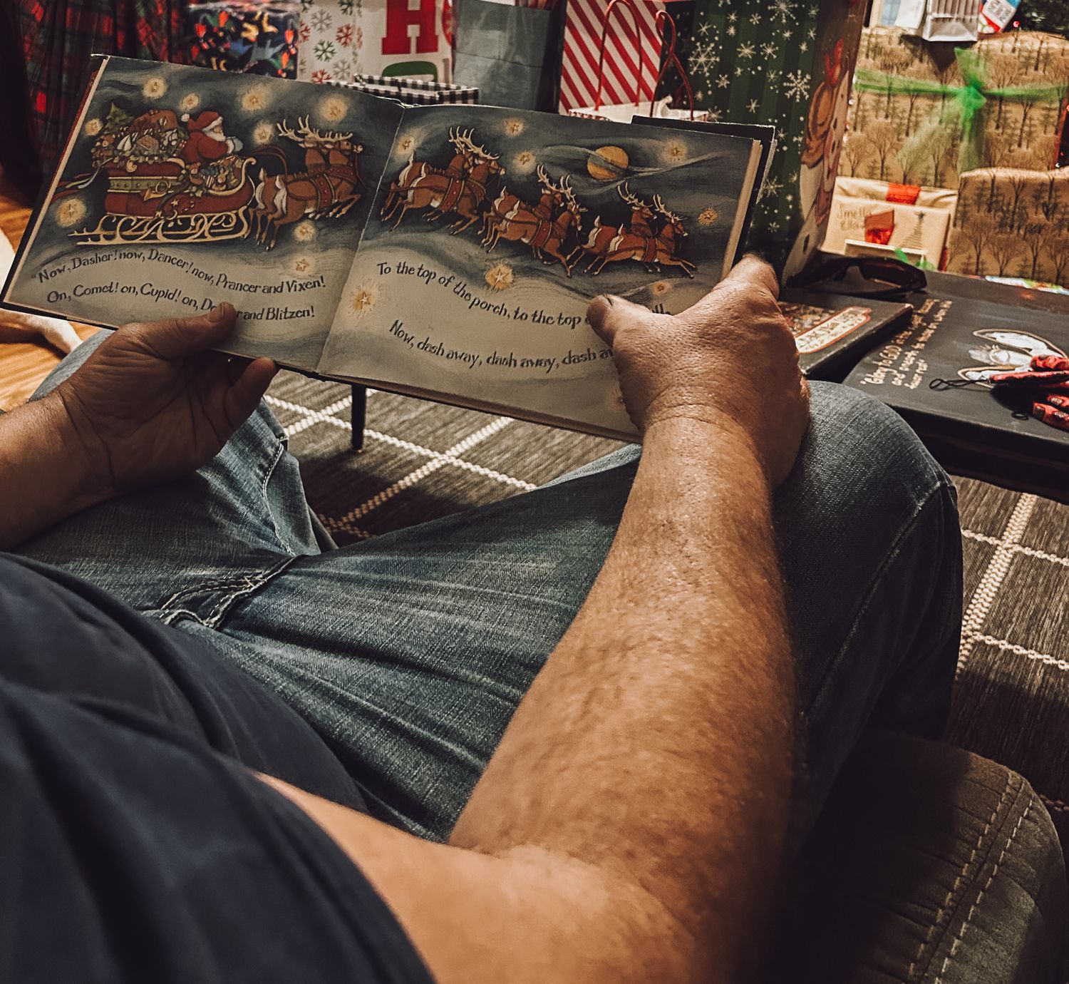 A person reads through an illustrated storybook while sitting down, with an American flag visible in the background.