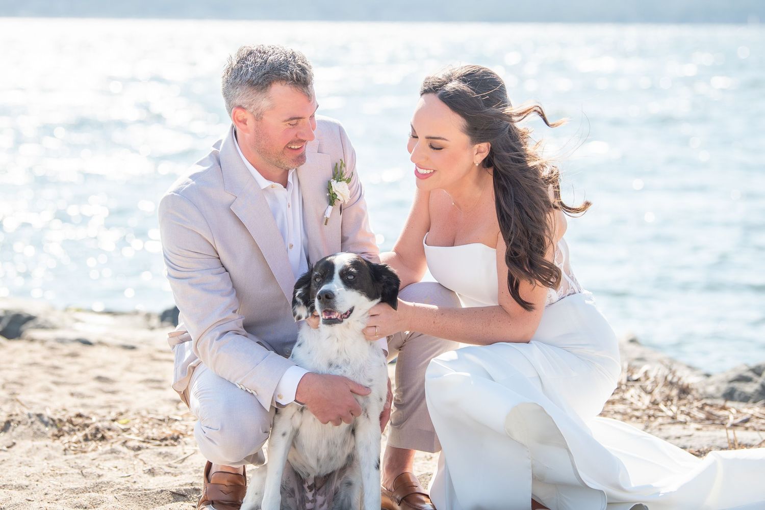 A couple shares romantic moments on a sunny beach during their wedding photoshoot.