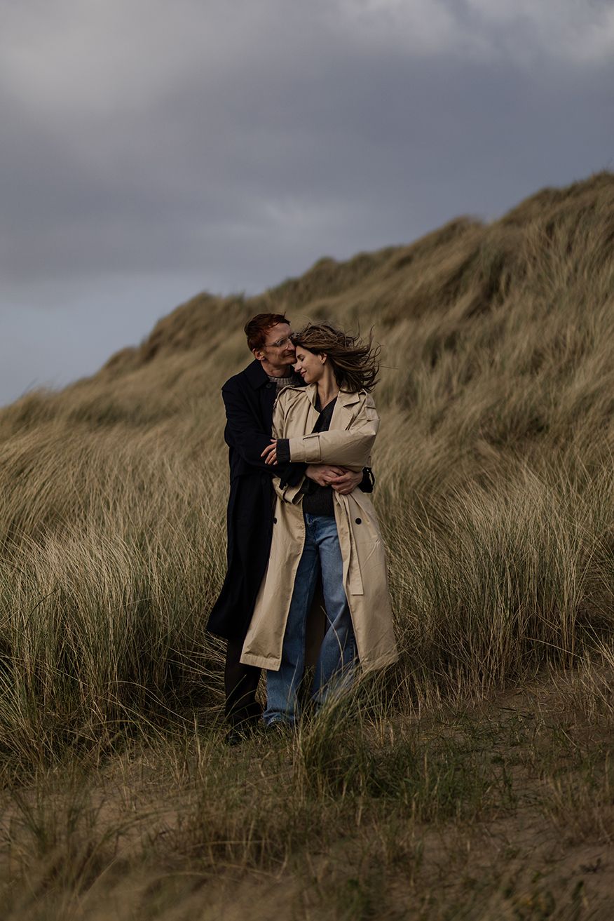 couple standing in dunes at Fanore beach, holding each other close during their couple photoshoot