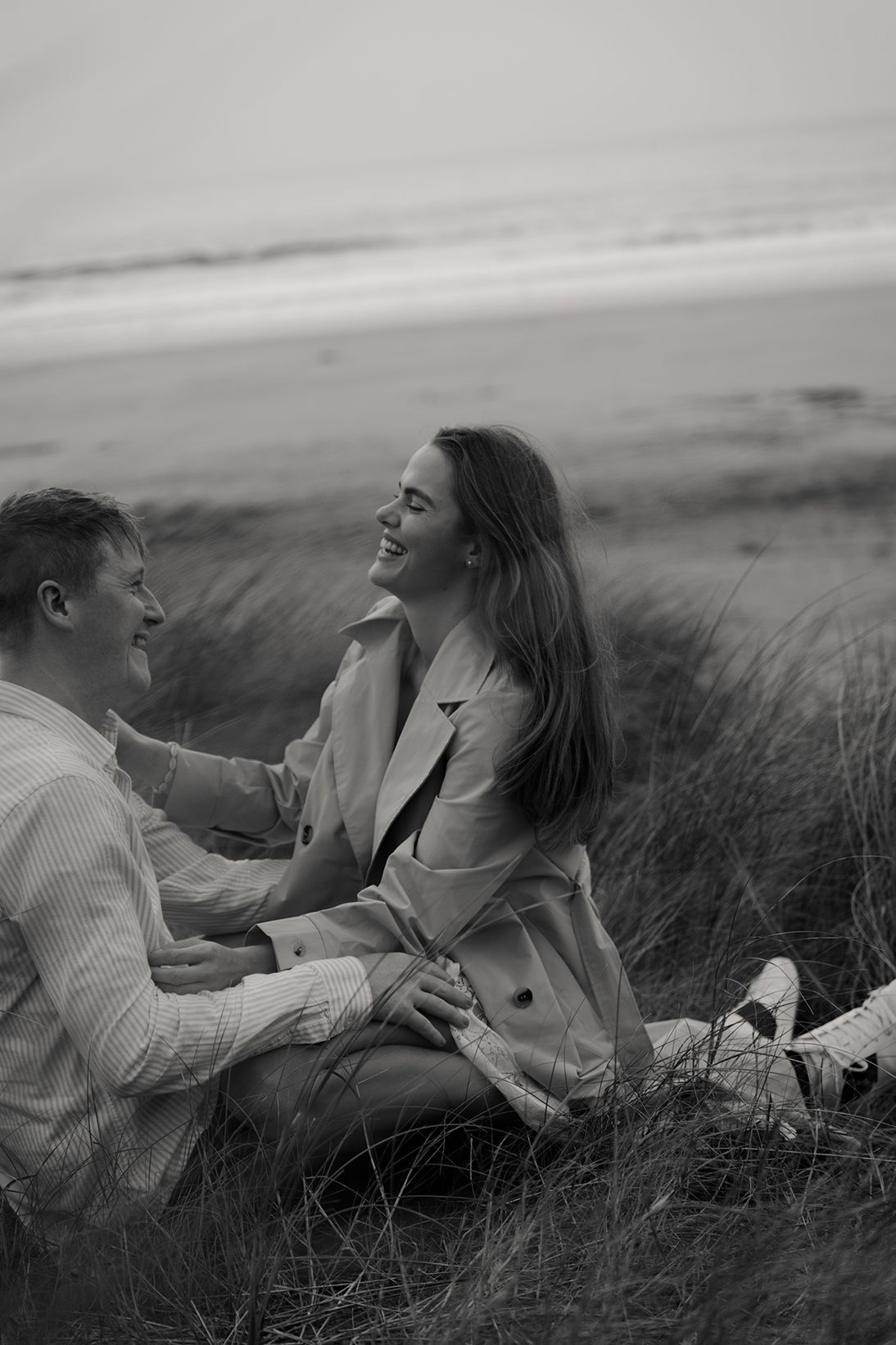 couple sitting on the beach in the sand, at Fanore beach during their photo session with a adventurous elopement photographer based Ireland