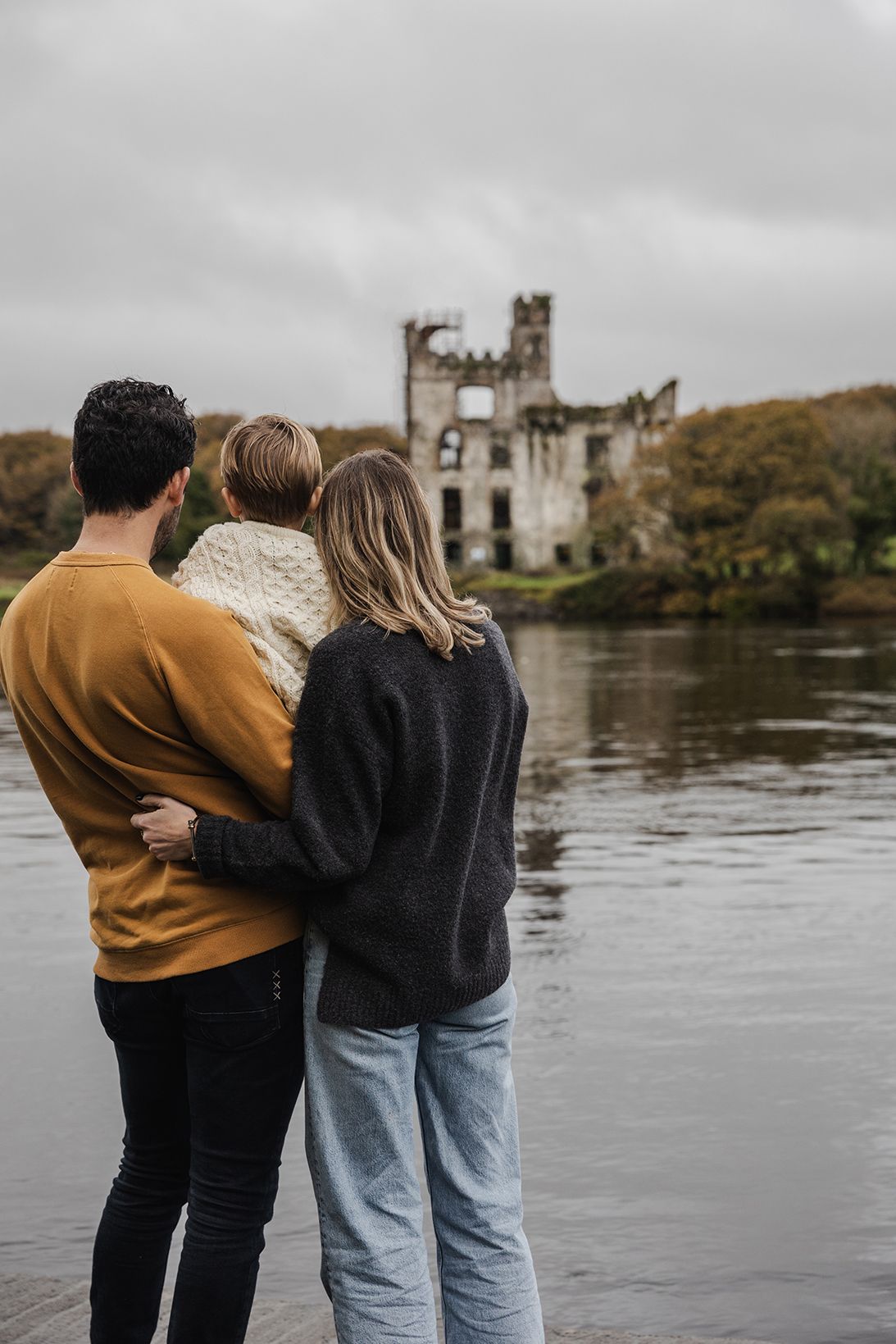 family standing and looking at Menlo castle in Galway, autumn, during their family photo session