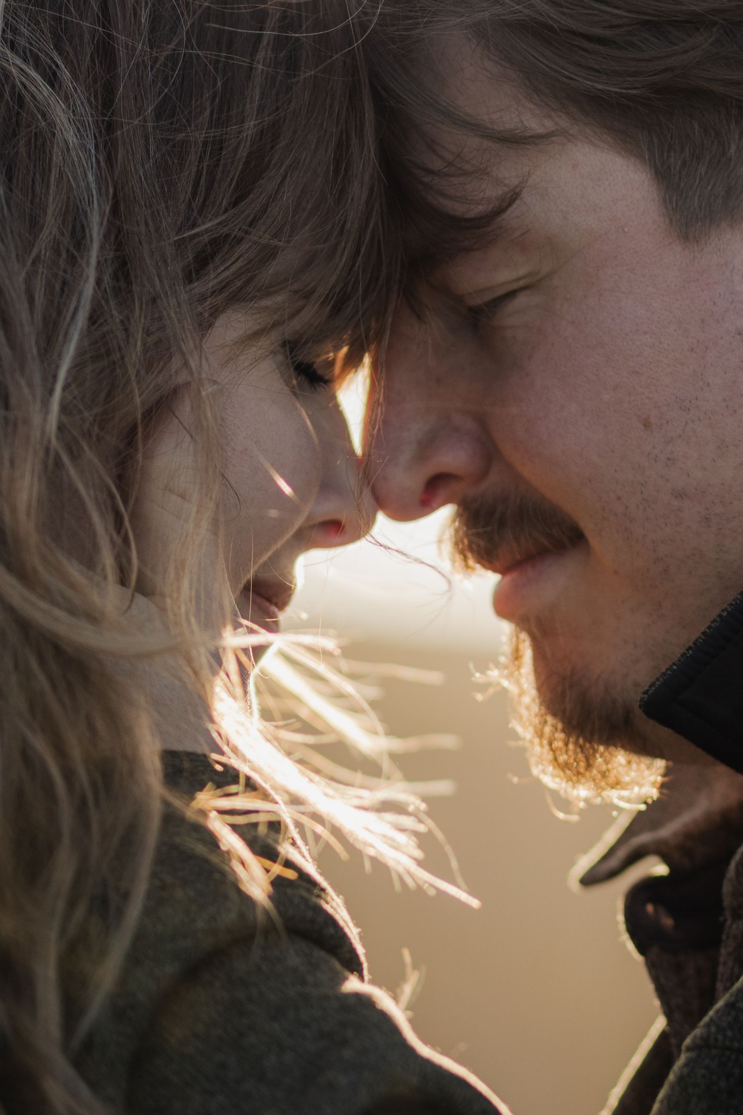 portrait of a couple at sunset during their adventure trip to Ireland, holding each other close, touching each others noses
