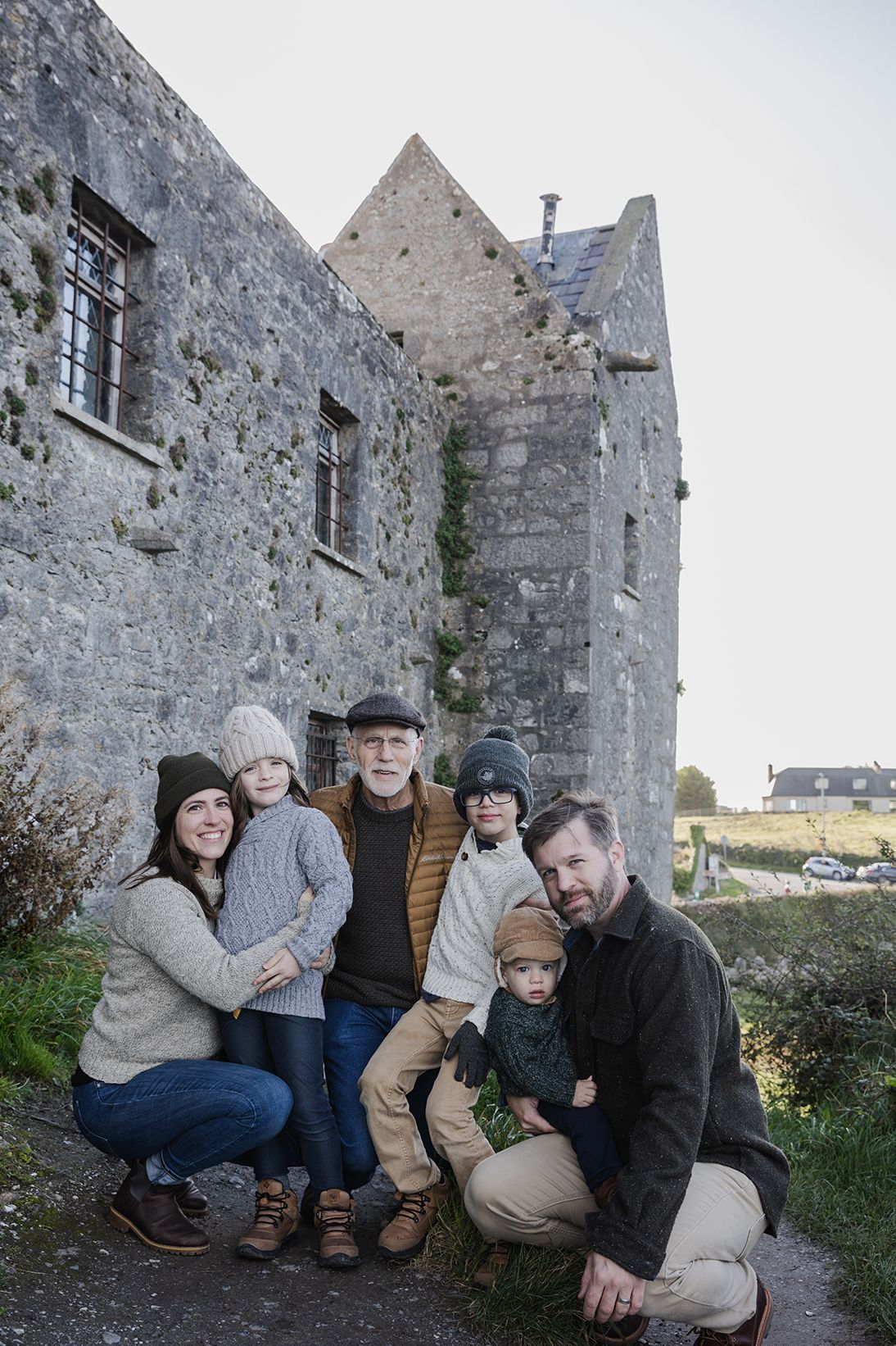 family standing close to each other posing at the Dunguaire castle during their family photo session, during their trip to Ireland