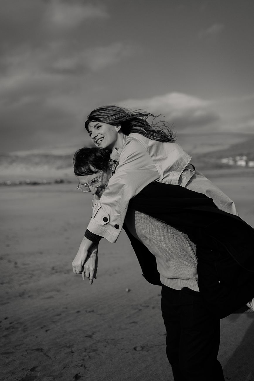 couple on the beach laughing, at Fanore beach during their photo session with a adventurous elopement photographer based in Ireland