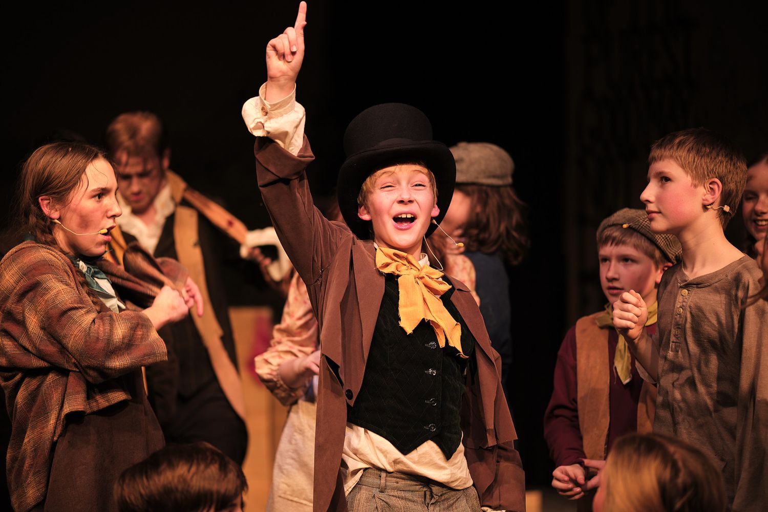 Theater performance featuring actors in period costumes with one enthusiastically gesturing upward.