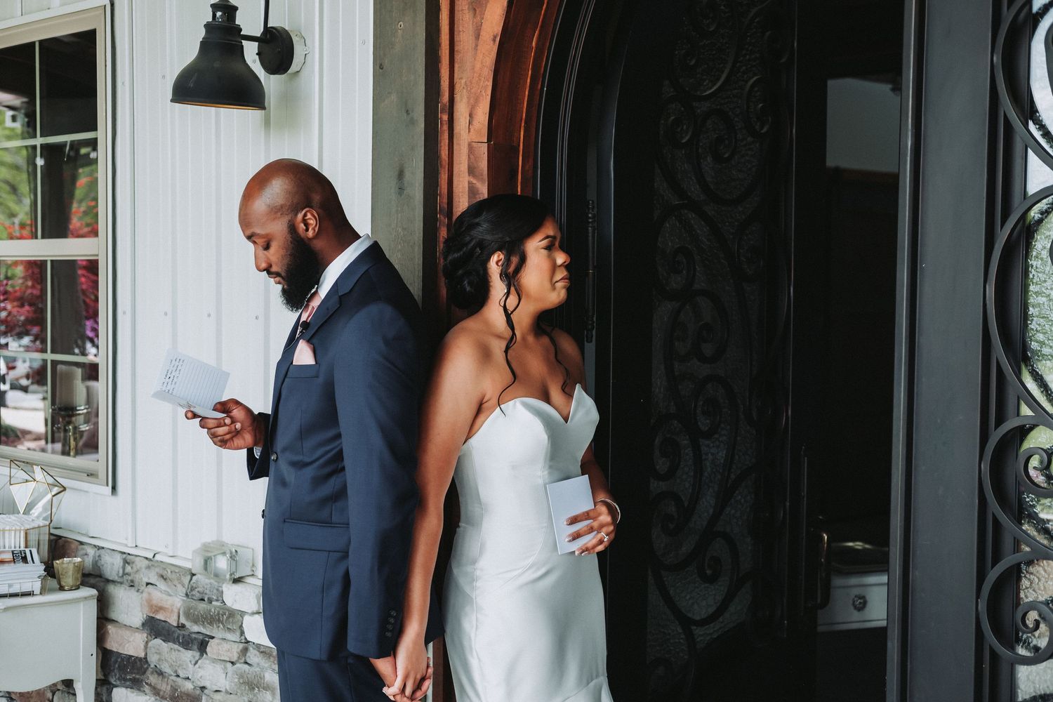 A couple embraces on their wedding day in front of ornate doors while a photographer captures their special moment.