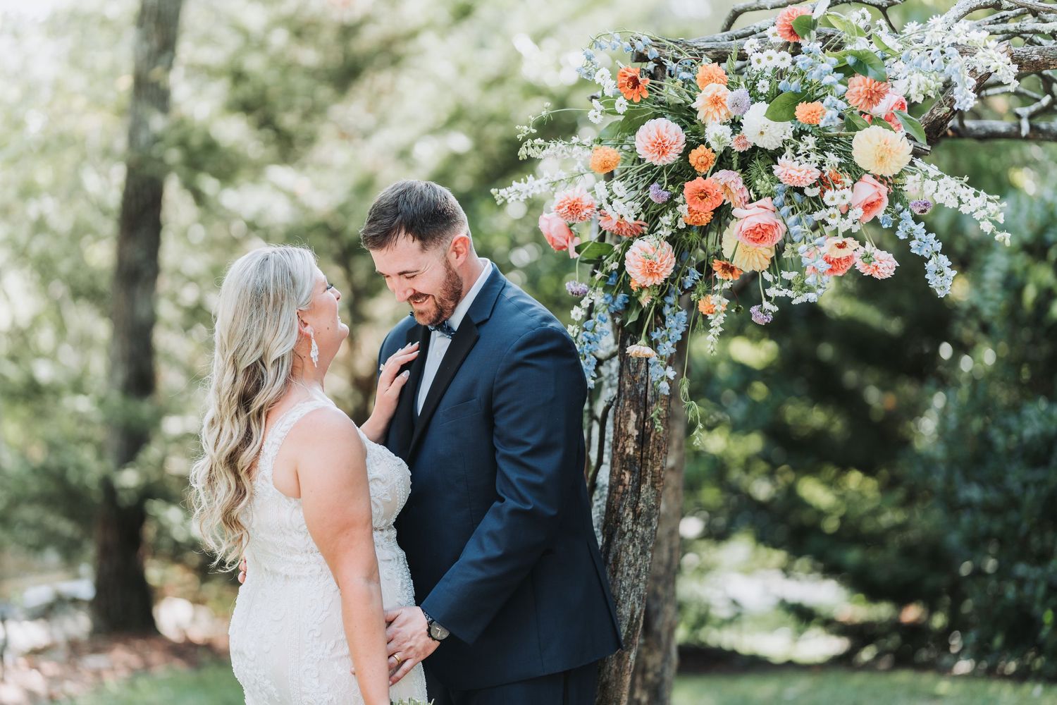 Romantic wedding portrait under floral arch with soft natural lighting.