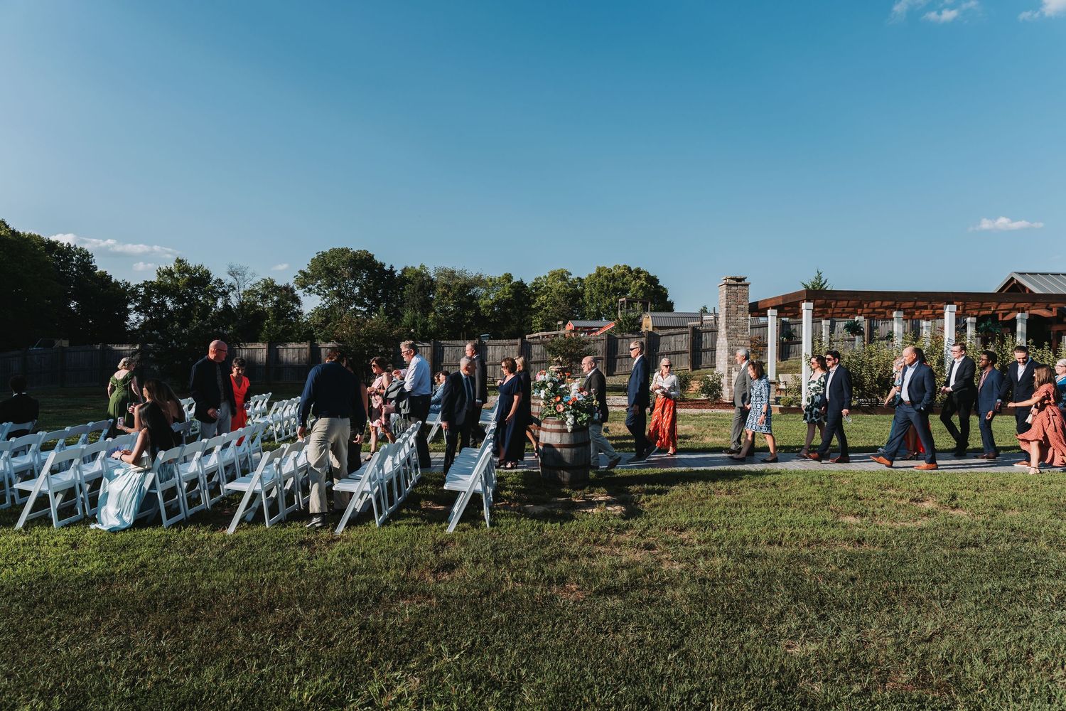 A panoramic view of people gathered on a grassy hillside for an outdoor event on a sunny day.