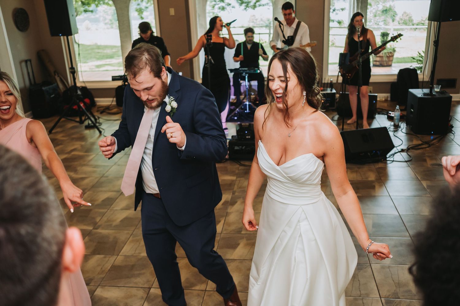 Two wedding guests dance together energetically on the dance floor during a wedding reception celebration.