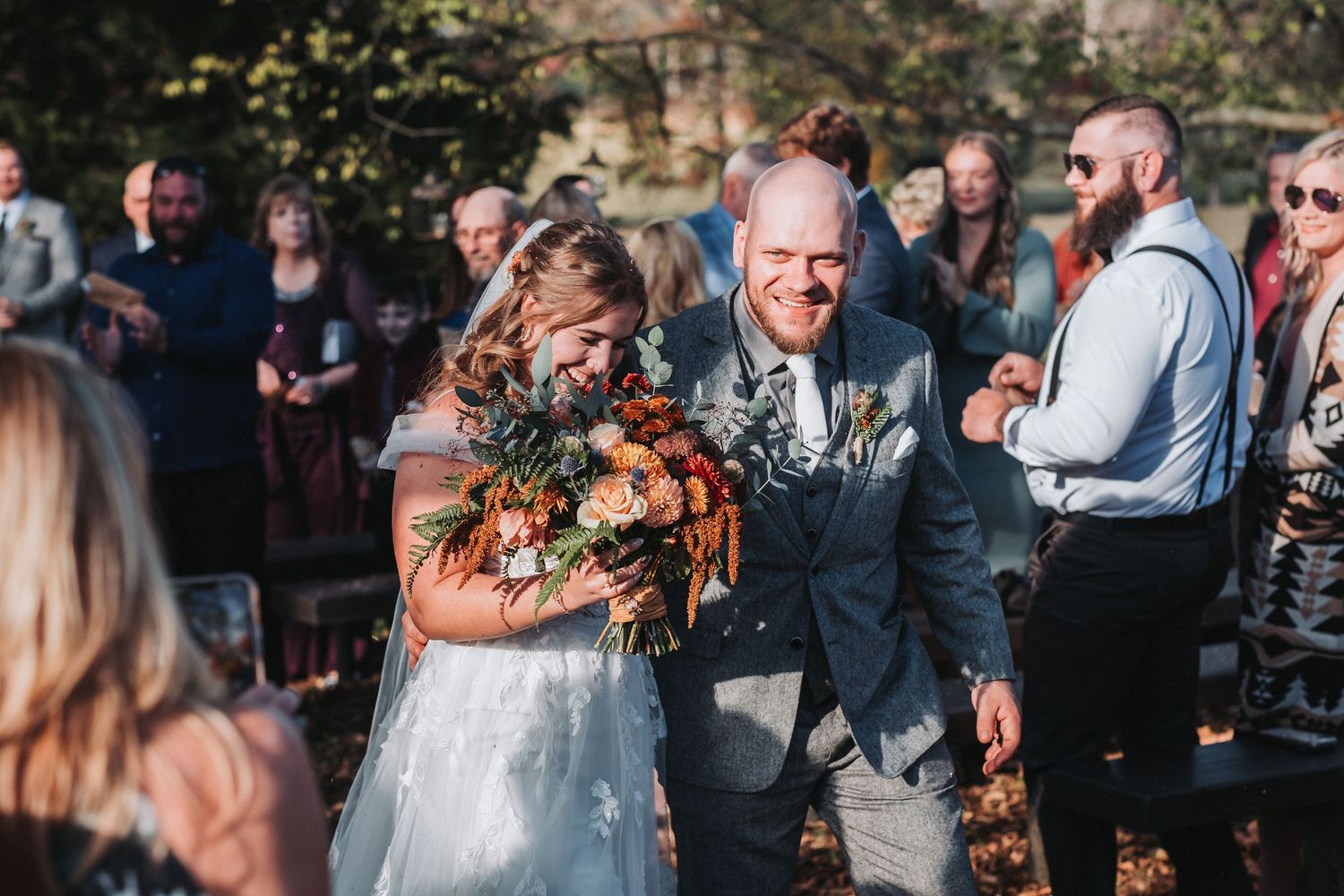 Wedding guests mingle and celebrate outdoors during a joyful reception with both indoor and outdoor seating areas.