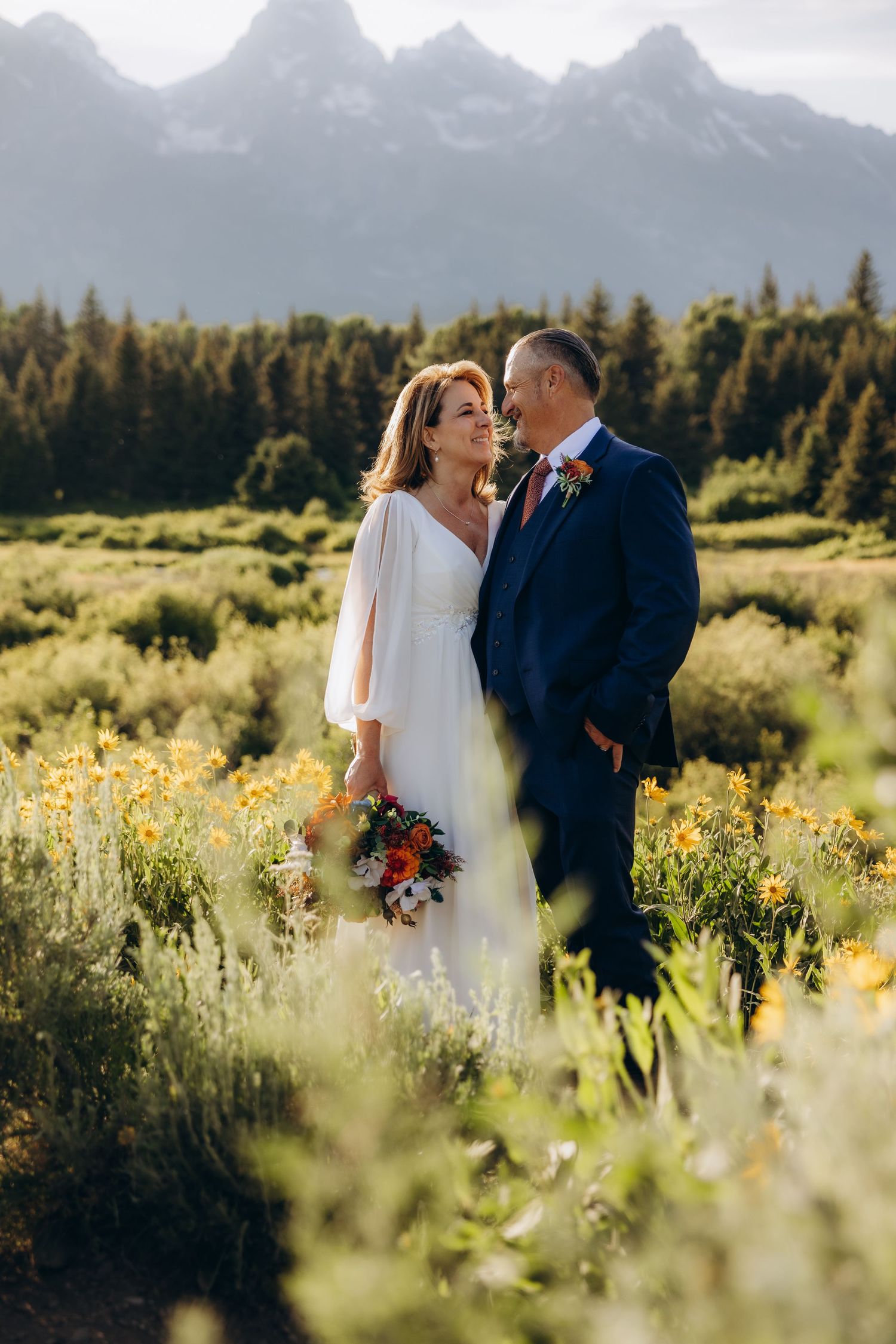 A couple shares romantic moments in a mountain meadow filled with wildflowers during their wedding photo session.