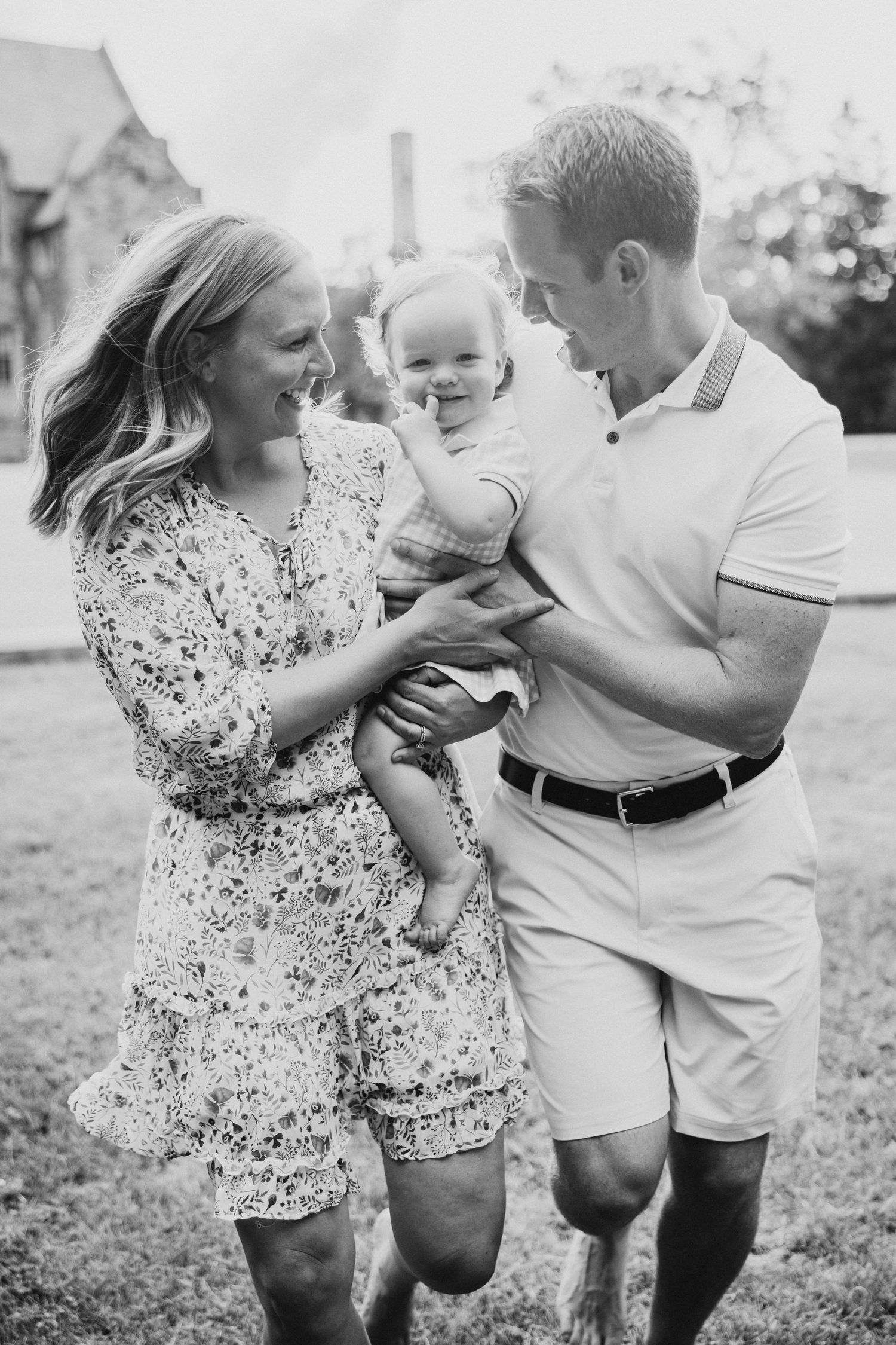 A family laughs together outdoors in a black and white candid photo.