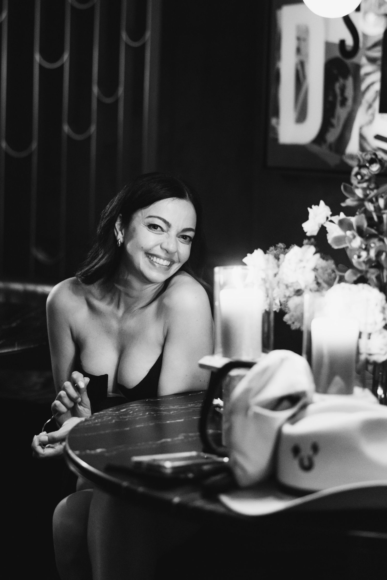 Atmospheric black and white portrait at a candlelit table with flowers, giving off vintage romantic vibes.