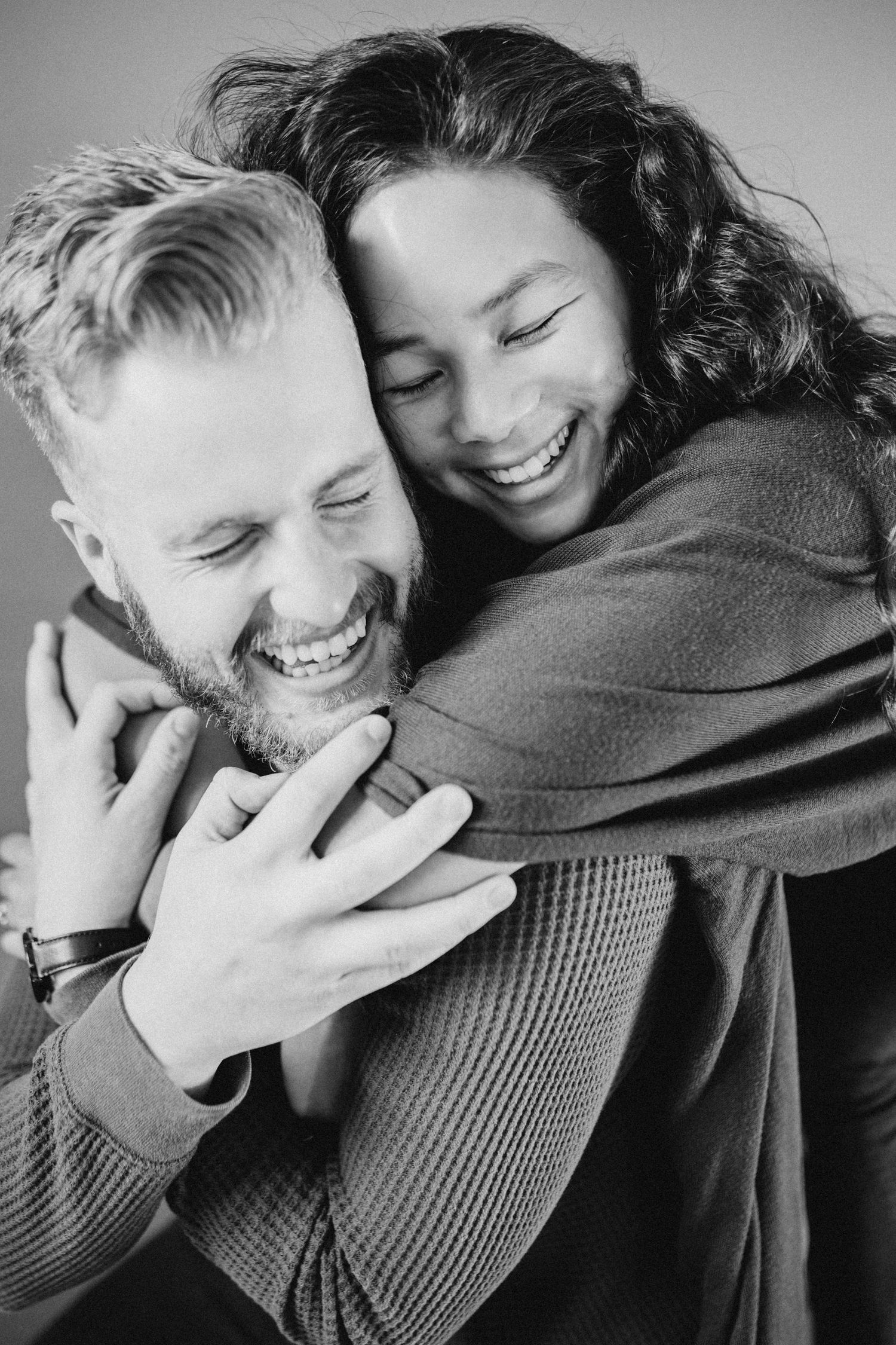 Black and white photo of couple sharing genuine laughter during intimate moment.