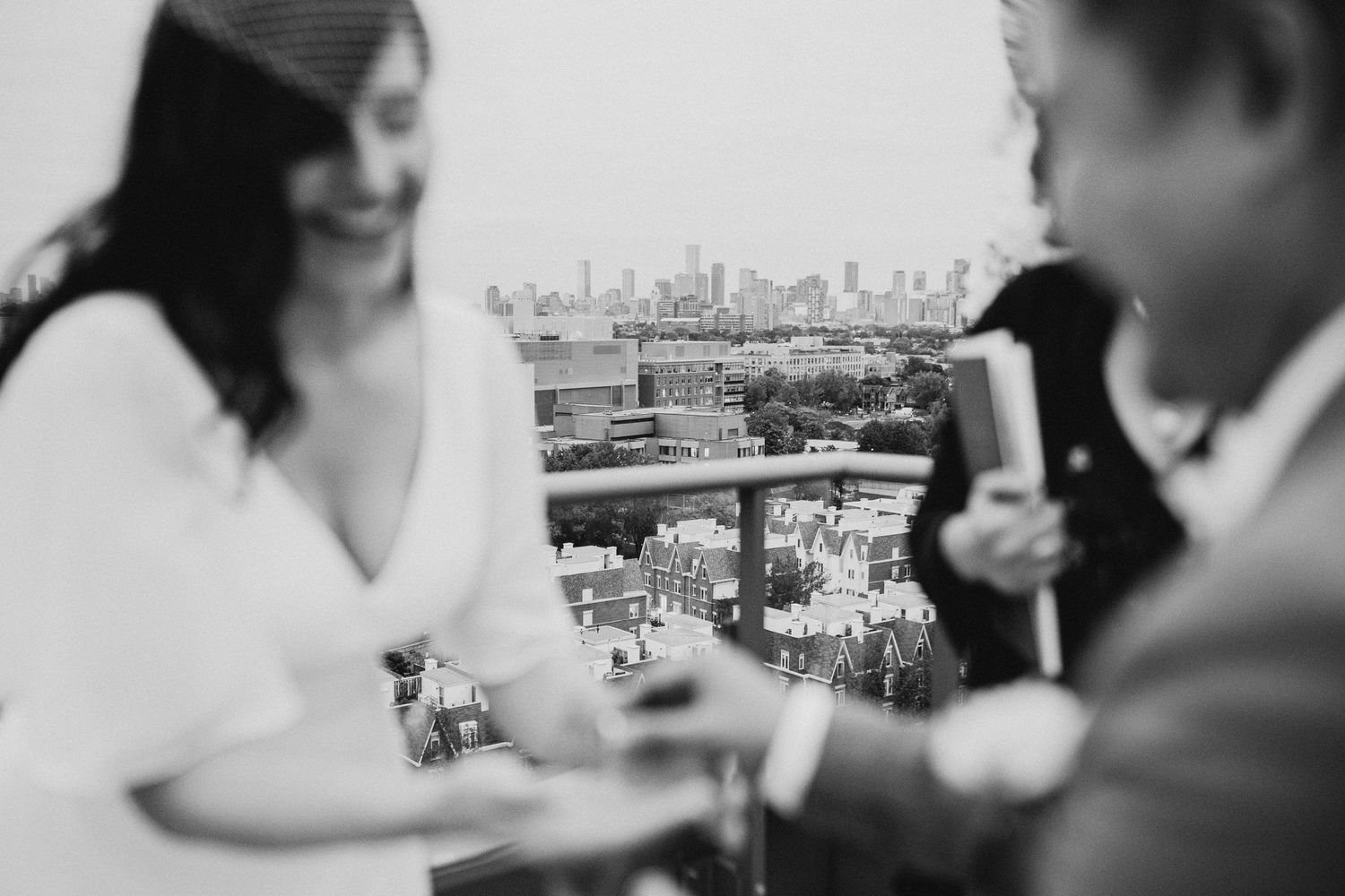 Couple enjoying drinks on a rooftop with city skyline in background.